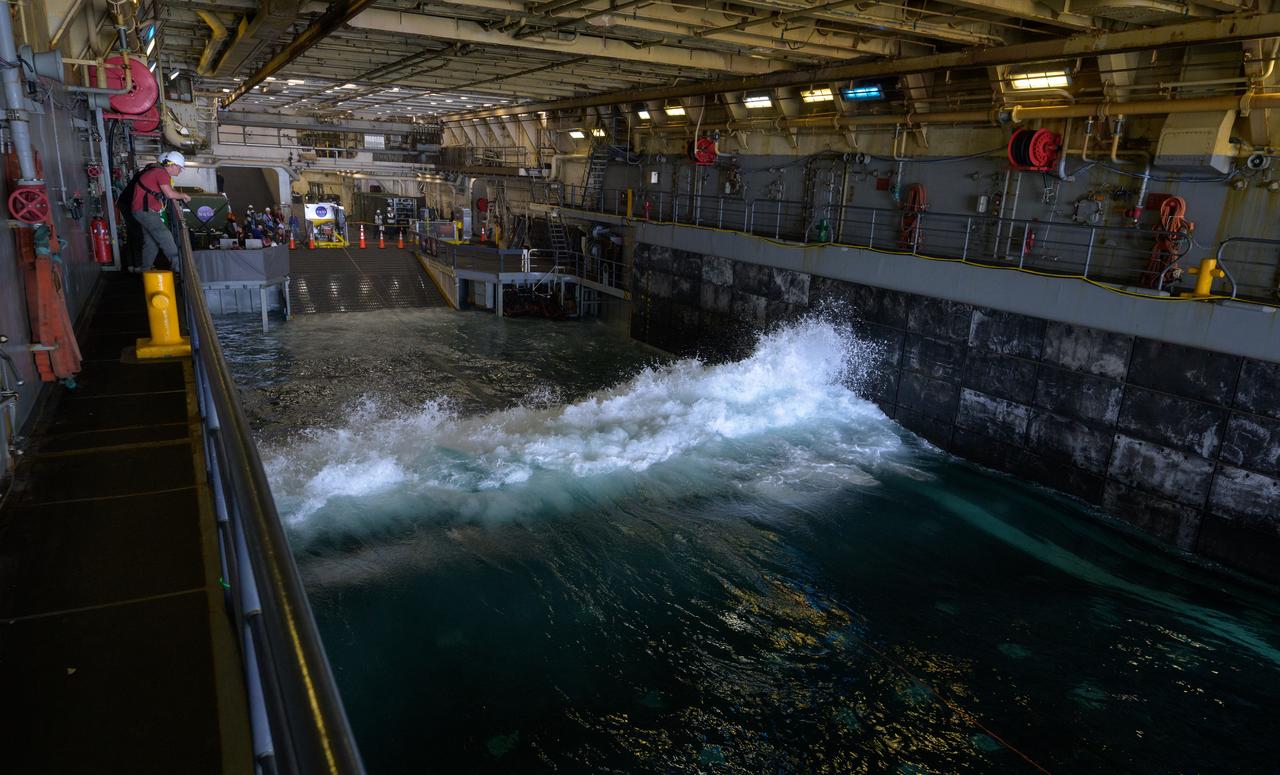 Waves come into the well deck of USS Somerset as teams deploy the Crew Module Test Article (CMTA), a full scale mockup of the Orion spacecraft, during Underway Recovery Test-12 off the coast of California, Wednesday, March 26, 2025. During the test, NASA and Department of Defense teams are practicing to ensure recovery procedures are validated as NASA plans to send Artemis II astronauts around the Moon and splashdown in the Pacific Ocean.  Photo Credit: (NASA/Bill Ingalls)