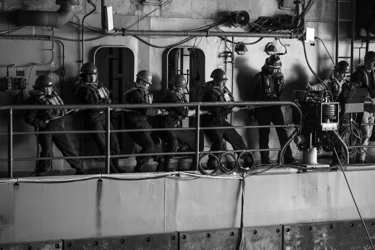 Mission support teams are seen toeing in rope line on USS Somerset as they practice with the Crew Module Test Article (CMTA), a full scale mockup of the Orion spacecraft, during Underway Recovery Test-12 off the coast of California, Wednesday, March 26, 2025. During the test, NASA and Department of Defense teams are practicing to ensure recovery procedures are validated as NASA plans to send Artemis II astronauts around the Moon and splashdown in the Pacific Ocean.  Photo Credit: (NASA/Bill Ingalls)