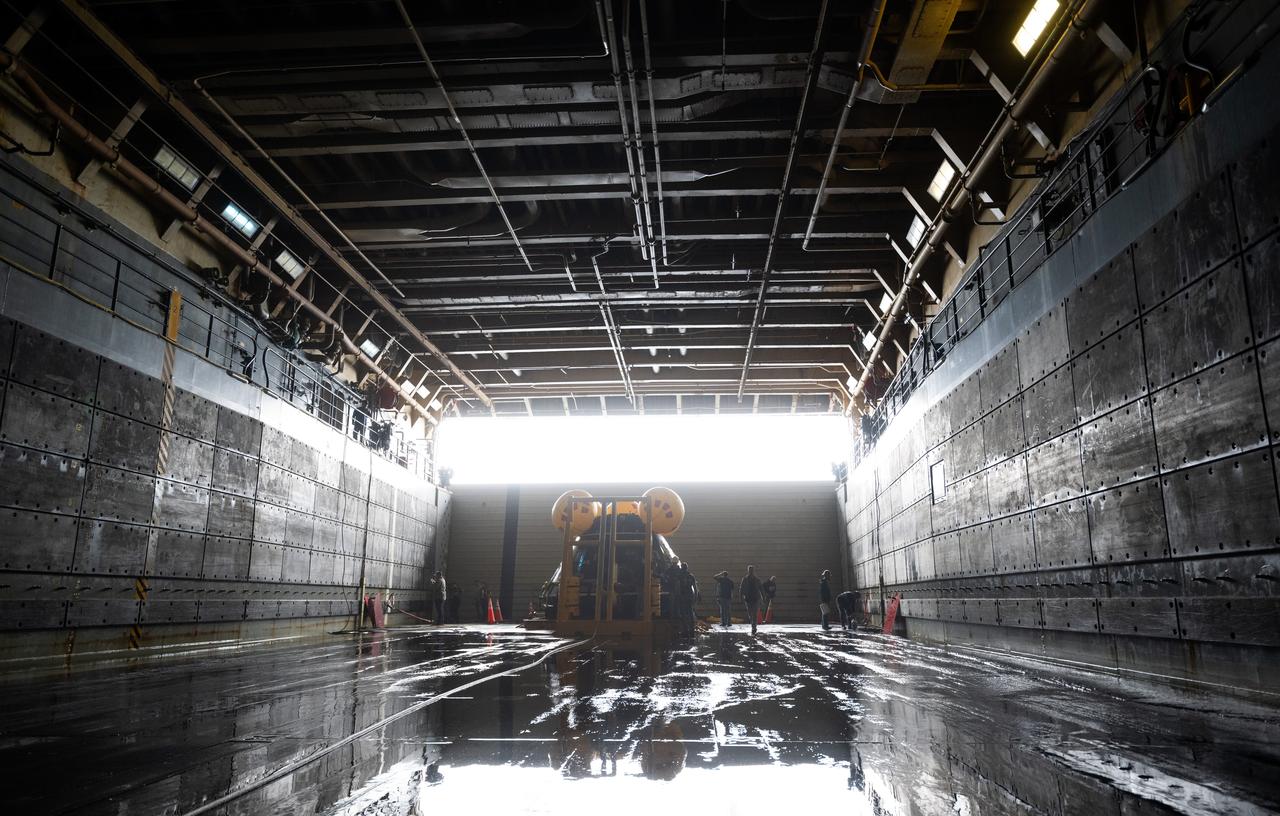 Teams work around the Crew Module Test Article (CMTA), a full scale mockup of the Orion spacecraft, as it sits nestled in its cradle following the completion of the days activities as part of Underway Recovery Test-12 onboard USS Somerset, Wednesday, March 26, 2025. During the test, NASA and Department of Defense teams are practicing to ensure recovery procedures are validated as NASA plans to send the Artemis II astronauts around the Moon and splashdown in the Pacific Ocean. Photo Credit: (NASA/Joel Kowsky)