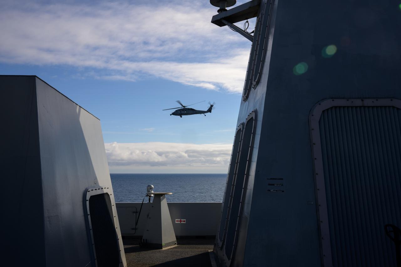 A Navy MH-60 Seahawk helicopter flies past USS Somerset off the coast of California, as NASA and Department of Defense teams participate in Underway Recovery Test-12, Thursday, March 27, 2025. During the test, teams are practicing to ensure recovery procedures are validated as NASA plans to send the Artemis II astronauts around the Moon and splashdown in the Pacific Ocean.  Photo Credit: (NASA/Bill Ingalls)
