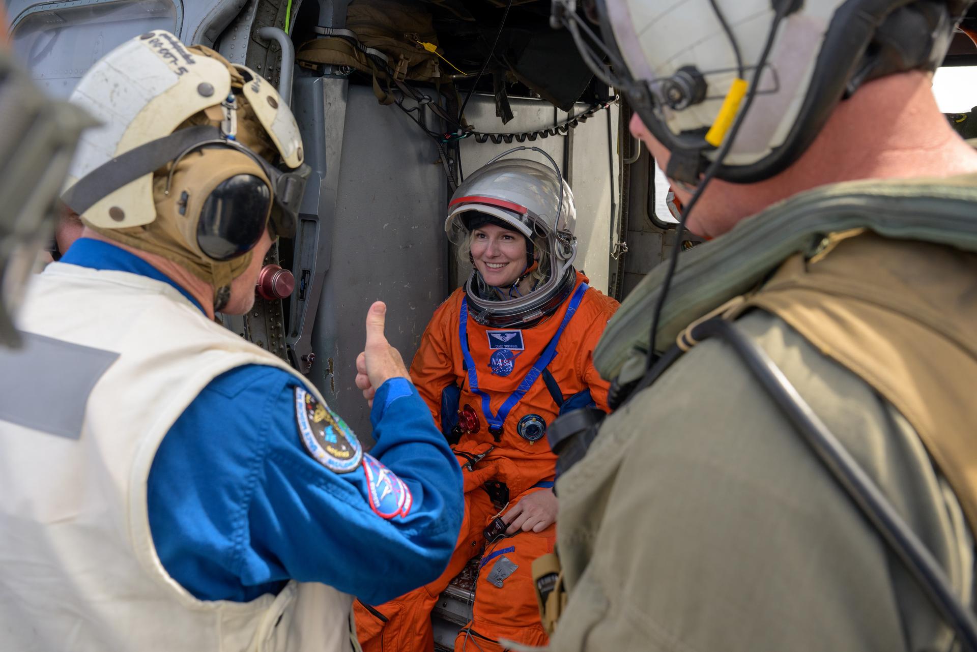 Image shows a man giving a thumbs up to a woman in an orange astronaut suit
