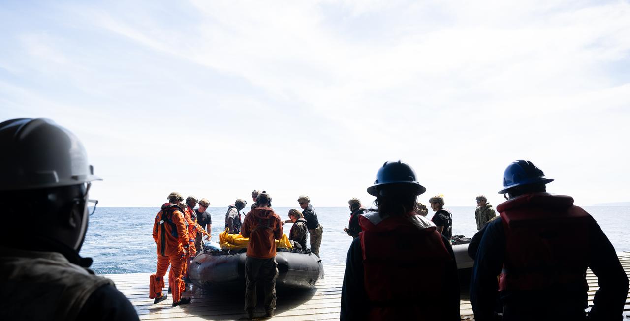 Navy Divers of Explosive Ordnance Disposal Expeditionary Support Unit (EODESU) 1 prepare to take NASA astronauts Andre Douglas, Deniz Burnham, and ESA (European Space Agency) astronaut Luca Parmitano out to the Crew Module Test Article (CMTA) as teams practice Artemis recovery operations during Underway Recovery Test-12 onboard USS Somerset off the coast of California, Thursday, March 27, 2025. During the test, NASA and Department of Defense teams are practicing to ensure recovery procedures are validated as NASA plans to send the Artemis II astronauts around the Moon and splashdown in the Pacific Ocean.  Photo Credit: (NASA/Joel Kowsky)