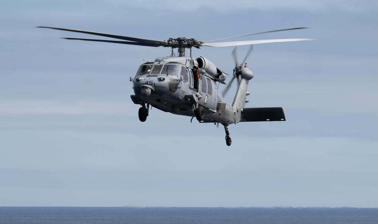 A Navy MH-60 Seahawk from Helicopter Sea Combat Squadron (HSC) 23 approaches USS Somerset after recovering crew from the Crew Module Test Article (CMTA), a full scale replica of the Orion spacecraft, during Underway Recovery Test-12, Thursday, March 27, 2025. During the test, NASA and Department of Defense teams are practicing to ensure recovery procedures are validated as NASA plans to send the Artemis II astronauts around the Moon and splashdown in the Pacific Ocean.  Photo Credit: (NASA/Joel Kowsky)