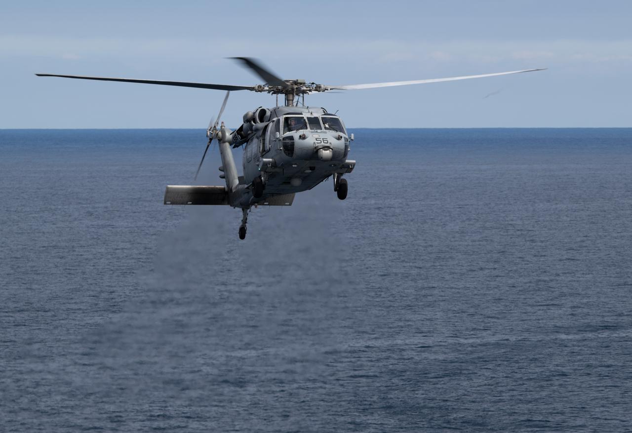 A Navy MH-60 Seahawk from Helicopter Sea Combat Squadron (HSC) 23 approaches USS Somerset after recovering crew from the Crew Module Test Article (CMTA), a full scale replica of the Orion spacecraft, during Underway Recovery Test-12, Thursday, March 27, 2025. During the test, NASA and Department of Defense teams are practicing to ensure recovery procedures are validated as NASA plans to send the Artemis II astronauts around the Moon and splashdown in the Pacific Ocean.  Photo Credit: (NASA/Joel Kowsky)