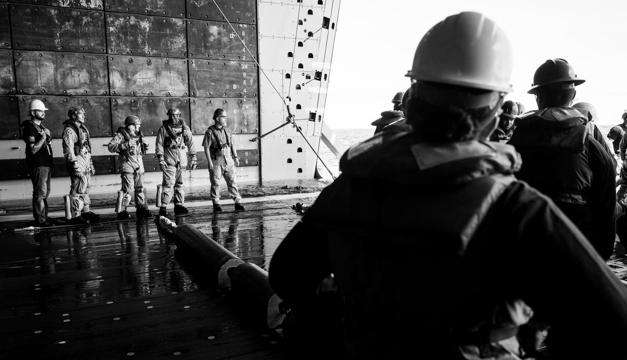 Grant Bruner, left, and Gary Kirkendall, right, Orion suit technicians, are seen with ESA (European Space Agency) astronaut Luca Parmitano, second from left, and NASA astronauts Deniz Burnham, center, and Andre Douglas, as they prepare to participate in Artemis recovery operations as part of Underway Recovery Test-12 onboard USS Somerset, Thursday, March 27, 2025. During the test, NASA and Department of Defense teams are practicing to ensure recovery procedures are validated as NASA plans to send the Artemis II astronauts around the Moon and splashdown in the Pacific Ocean.  Photo Credit: (NASA/Joel Kowsky)
