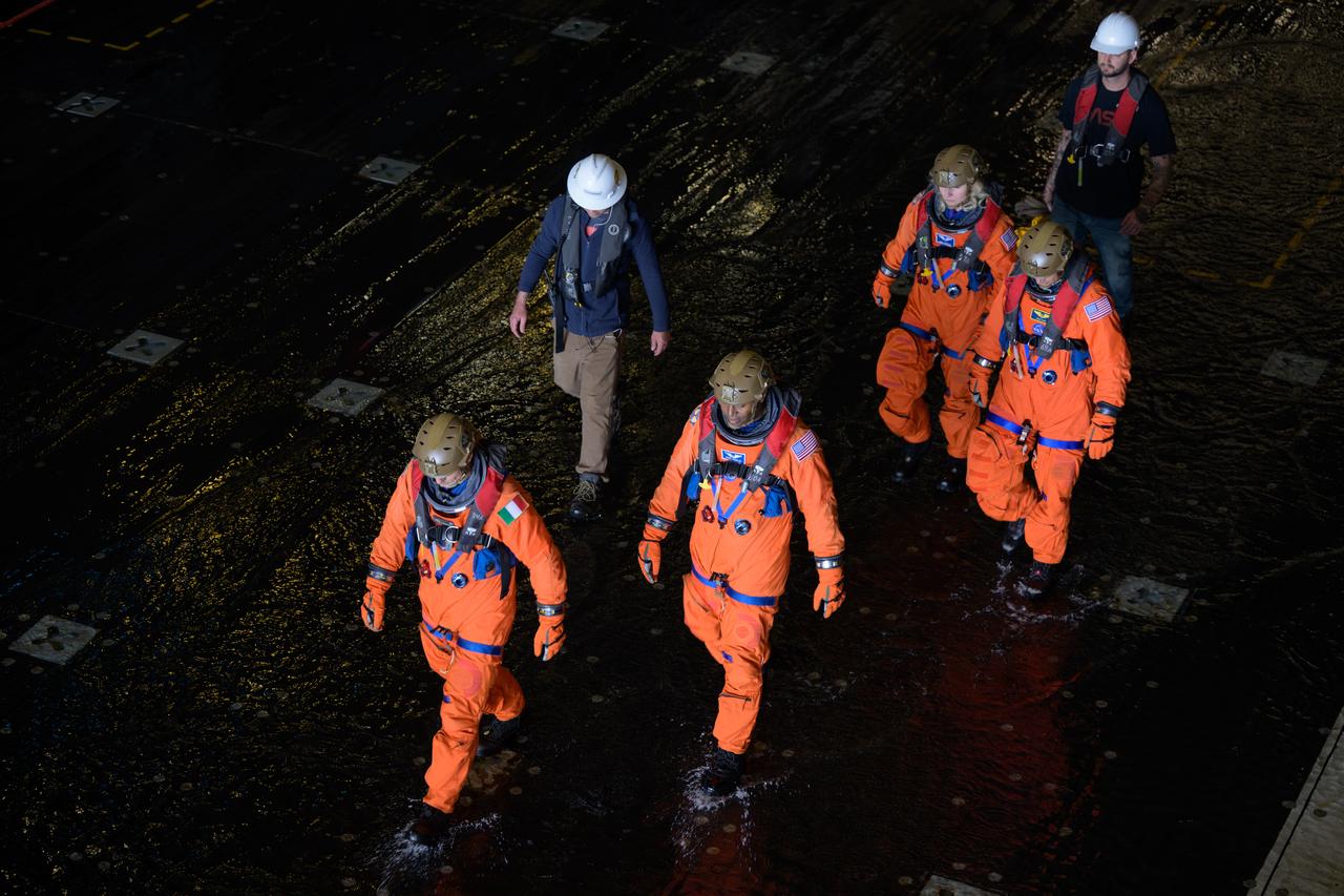ESA (European Space Agency) astronaut Luca Parmitano, left, and NASA astronauts Andre Douglas, Deniz Burnham, and Stan Love, right, walk in the well of USS Somerset to catch boats to the Crew Module Test Article (CMTA), a full scale mockup of the Orion spacecraft, during Underway Recovery Test-12 off the coast of California, Friday, March 28, 2025. During the test, NASA and Department of Defense teams are practicing to ensure recovery procedures are validated as NASA plans to send Artemis II astronauts around the Moon and splashdown in the Pacific Ocean.  Photo Credit: (NASA/Bill Ingalls)