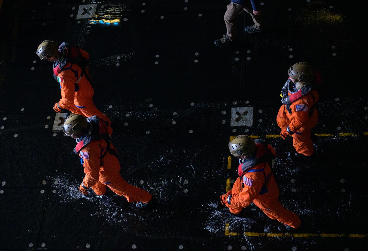 ESA (European Space Agency) astronaut Luca Parmitano, left, and NASA astronauts Andre Douglas, Stan Love,, and Deniz Burnham, right, walk in the well of USS Somerset to catch boats to the Crew Module Test Article (CMTA), a full scale mockup of the Orion spacecraft, during Underway Recovery Test-12 off the coast of California, Friday, March 28, 2025. During the test, NASA and Department of Defense teams are practicing to ensure recovery procedures are validated as NASA plans to send Artemis II astronauts around the Moon and splashdown in the Pacific Ocean.  Photo Credit: (NASA/Bill Ingalls)