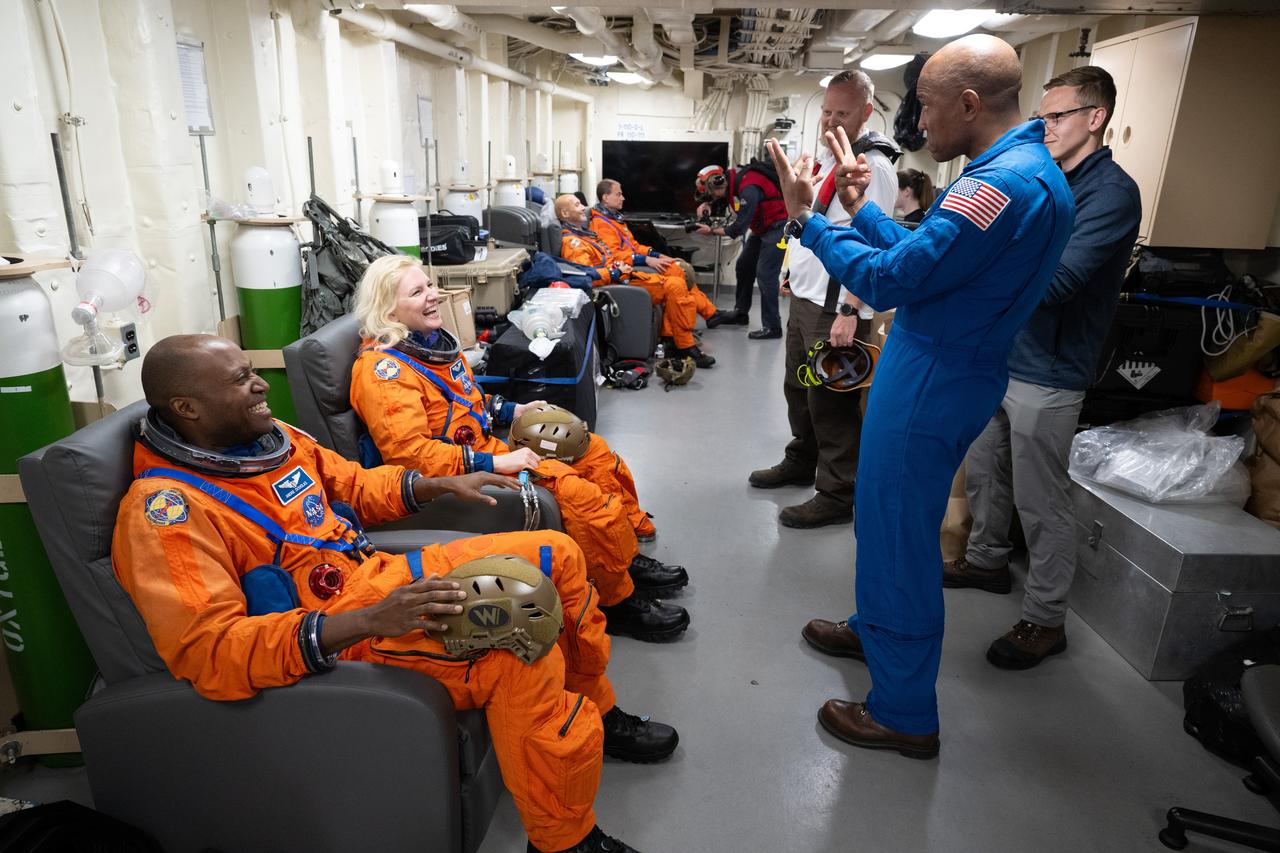 NASA astronaut and Artemis II pilot Victor Glover, right, speaks to NASA astronauts Andre Douglas and Deniz Burnham as they prepare to take part in practicing Artemis recovery procedures during Underway Recovery Test-12 onboard USS Somerset off the coast of California, Friday, March 28, 2025. During the test, NASA and Department of Defense teams are practicing to ensure recovery procedures are validated as NASA plans to send the Artemis II astronauts around the Moon and splashdown in the Pacific Ocean.  Photo Credit: (NASA/Joel Kowsky)