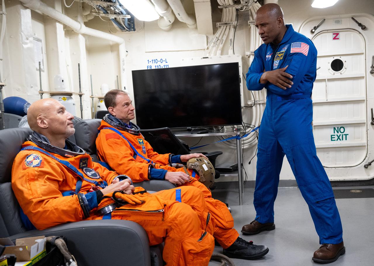 NASA astronaut and Artemis II pilot Victor Glover, right, speaks to ESA (European Space Agency) astronaut Luca Parmitano, left, and NASA astronaut Stan Love as they prepare to take part in practicing Artemis recovery procedures during Underway Recovery Test-12 onboard USS Somerset off the coast of California, Friday, March 28, 2025. During the test, NASA and Department of Defense teams are practicing to ensure recovery procedures are validated as NASA plans to send the Artemis II astronauts around the Moon and splashdown in the Pacific Ocean. Photo Credit: (NASA/Joel Kowsky)