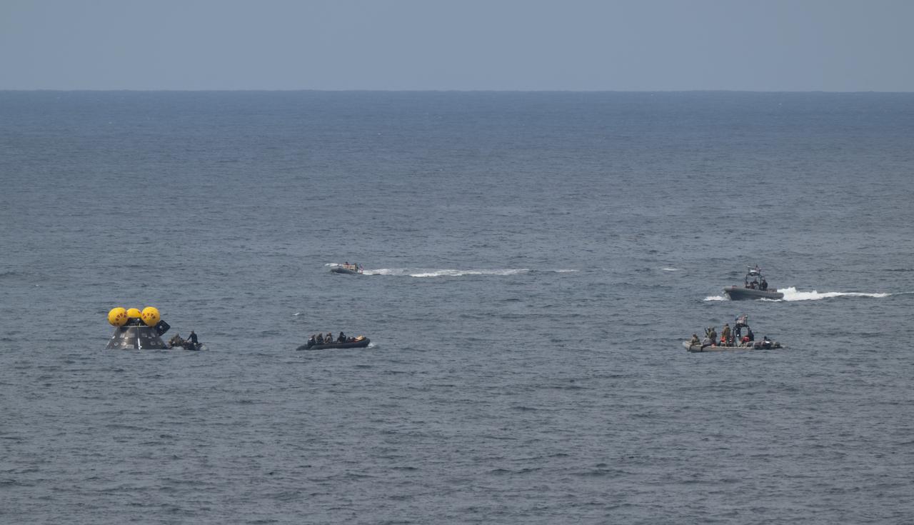 Teams work around the Crew Module Test Article (CMTA) as they practice Artemis recovery operations during Underway Recovery Test-12 onboard USS Somerset off the coast of California, Friday, March 28, 2025. During the test, NASA and Department of Defense teams are practicing to ensure recovery procedures are validated as NASA plans to send the Artemis II astronauts around the Moon and splashdown in the Pacific Ocean.  Photo Credit: (NASA/Joel Kowsky)