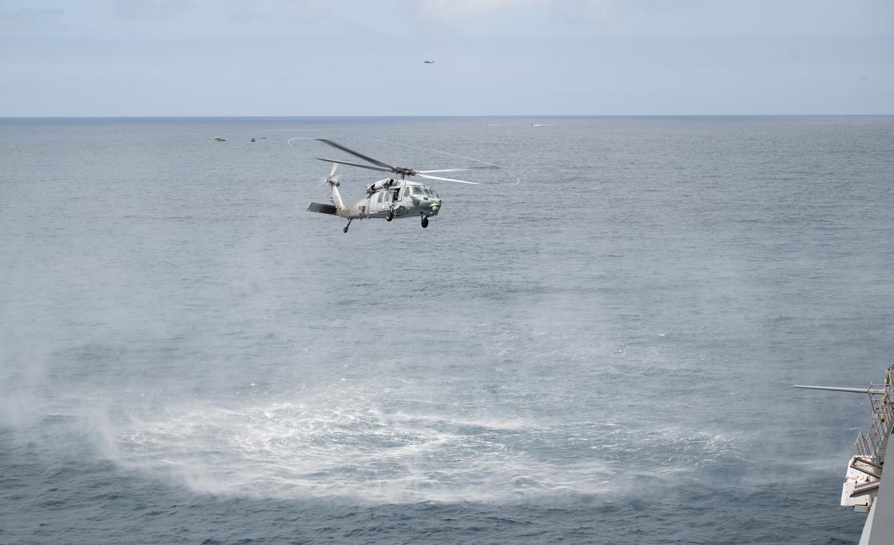 A Navy MH-60 Seahawk from Helicopter Sea Combat Squadron (HSC) 23 returns to USS Somerset as teams practice Artemis recovery operations during Underway Recovery Test-12 off the coast of California, Friday, March 28, 2025. During the test, NASA and Department of Defense teams are practicing to ensure recovery procedures are validated as NASA plans to send the Artemis II astronauts around the Moon and splashdown in the Pacific Ocean.  Photo Credit: (NASA/Joel Kowsky)