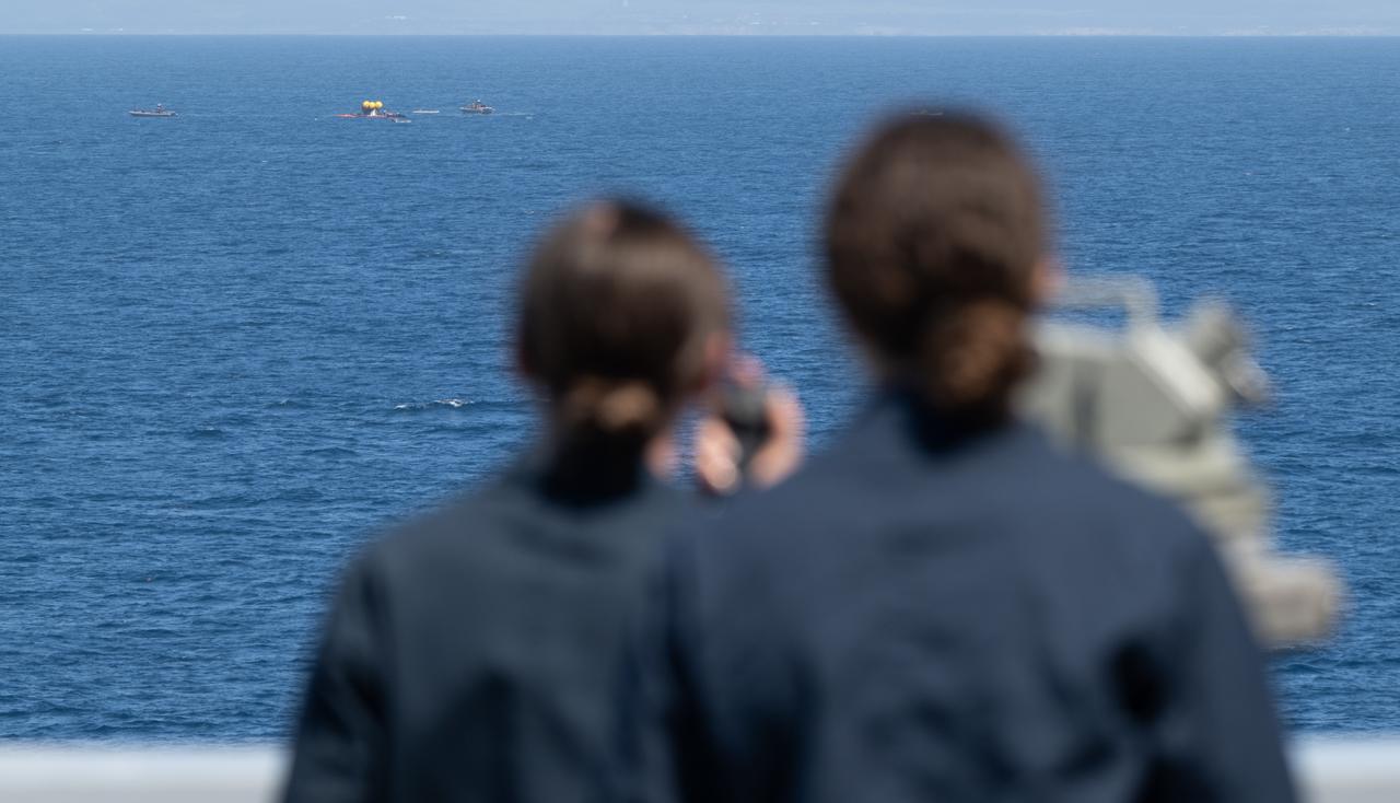 Teams work around the Crew Module Test Article (CMTA) as they practice Artemis recovery operations during Underway Recovery Test-12 onboard USS Somerset off the coast of California, Friday, March 28, 2025. During the test, NASA and Department of Defense teams are practicing to ensure recovery procedures are validated as NASA plans to send the Artemis II astronauts around the Moon and splashdown in the Pacific Ocean.  Photo Credit: (NASA/Joel Kowsky)