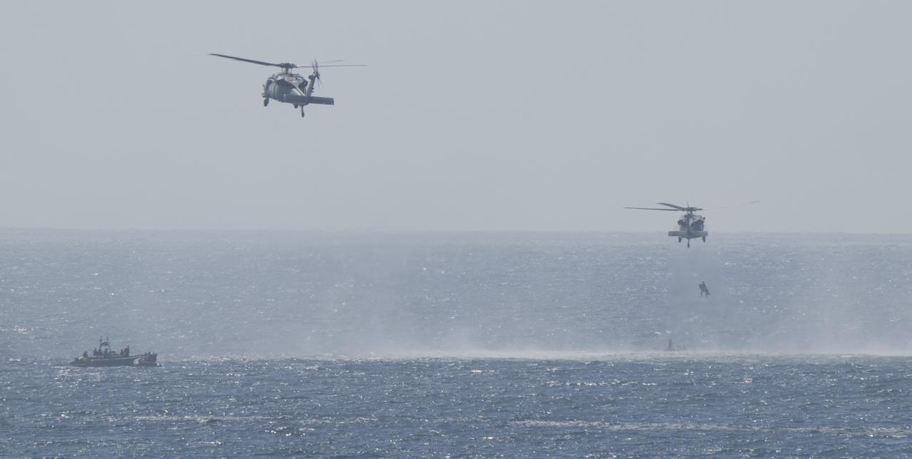 A pair of Navy MH-60 Seahawks from Helicopter Sea Combat Squadron (HSC) 23 are seen as they recover astronauts from the Crew Module Test Article (CMTA) as teams practice Artemis recovery operations during Underway Recovery Test-12 off the coast of California, Friday, March 28, 2025. During the test, NASA and Department of Defense teams are practicing to ensure recovery procedures are validated as NASA plans to send the Artemis II astronauts around the Moon and splashdown in the Pacific Ocean.  Photo Credit: (NASA/Joel Kowsky)
