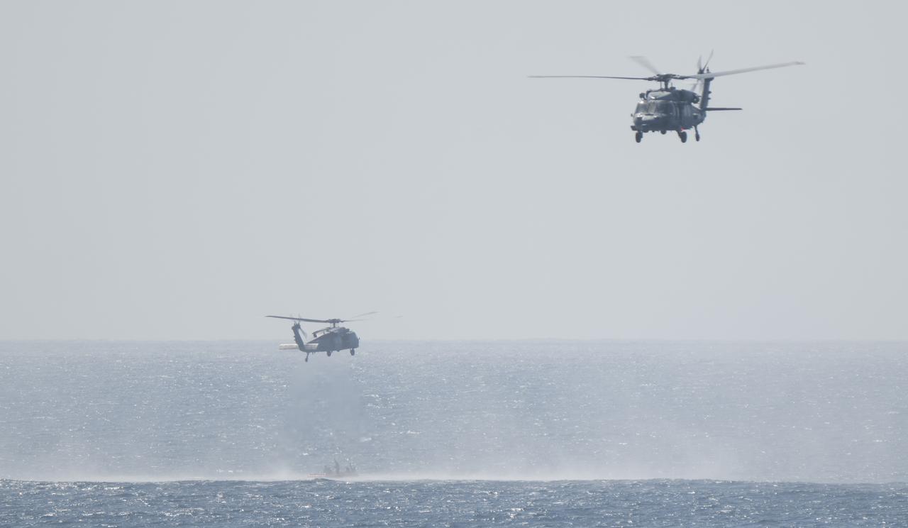 A pair of Navy MH-60 Seahawks from Helicopter Sea Combat Squadron (HSC) 23 are seen as they recover astronauts from the Crew Module Test Article (CMTA) as teams practice Artemis recovery operations during Underway Recovery Test-12 off the coast of California, Friday, March 28, 2025. During the test, NASA and Department of Defense teams are practicing to ensure recovery procedures are validated as NASA plans to send the Artemis II astronauts around the Moon and splashdown in the Pacific Ocean.  Photo Credit: (NASA/Joel Kowsky)