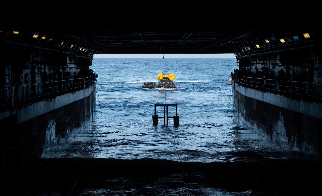 Teams work to recover the Crew Module Test Article (CMTA) as they practice Artemis recovery procedures during Underway Recovery Test-12 onboard USS Somerset off the coast of California, Friday, March 28, 2025. During the test, NASA and Department of Defense teams are practicing to ensure recovery procedures are validated as NASA plans to send the Artemis II astronauts around the Moon and splashdown in the Pacific Ocean. Photo Credit: (NASA/Bill Ingalls and Joel Kowsky)