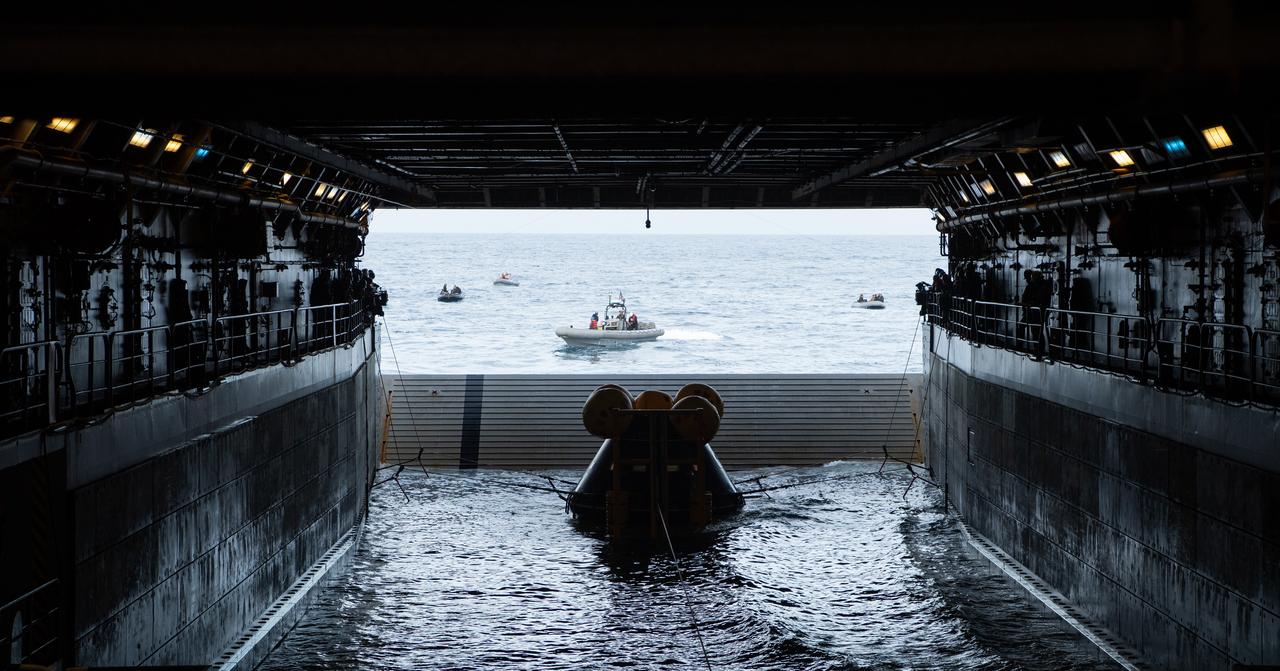 Teams work to recover the Crew Module Test Article (CMTA) as they practice Artemis recovery procedures during Underway Recovery Test-12 onboard USS Somerset off the coast of California, Friday, March 28, 2025. During the test, NASA and Department of Defense teams are practicing to ensure recovery procedures are validated as NASA plans to send the Artemis II astronauts around the Moon and splashdown in the Pacific Ocean. Photo Credit: (NASA/Bill Ingalls and Joel Kowsky)