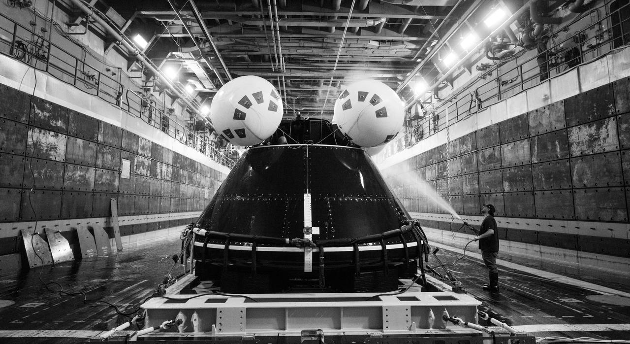 A member of NASA’s Landing and Recovery team washes saltwater off of the Crew Module Test Article (CMTA) after teams practiced recovery operations during Underway Recovery Test-12 onboard USS Somerset off the coast of California, Saturday, March 29, 2025. During the test, NASA and Department of Defense teams are practicing to ensure recovery procedures are validated as NASA plans to send the Artemis II astronauts around the Moon and splashdown in the Pacific Ocean. Photo Credit: (NASA/Joel Kowsky)