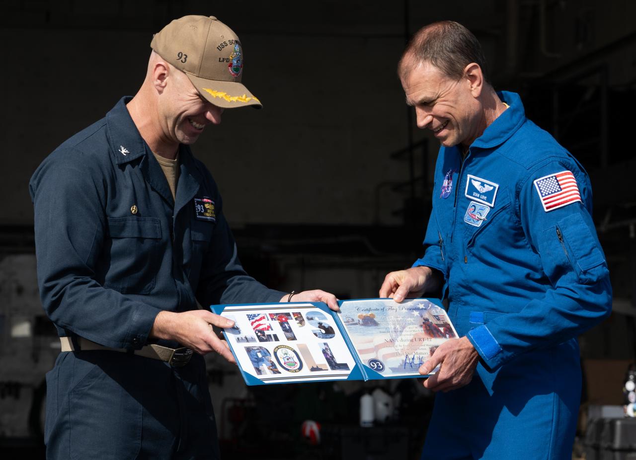 NASA astronaut Stan Love receives a presentation of a flown flag from Capt. Andrew Koy, commanding officer of USS Somerset as NASA and Department of Defense teams participate in Underway Recovery Test-12 onboard USS Somerset off the coast of California, Saturday, March 29, 2025. During the test, NASA and Department of Defense teams are practicing to ensure recovery procedures are validated as NASA plans to send the Artemis II astronauts around the Moon and splashdown in the Pacific Ocean.  Photo Credit: (NASA/Joel Kowsky)