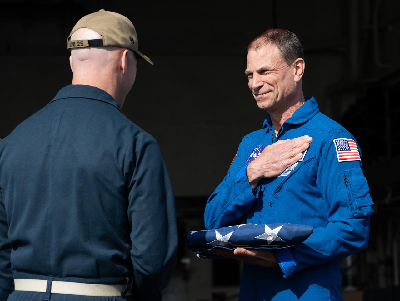 NASA astronaut Stan Love receives a presentation of a flag flown on USS Somerset from Capt. Andrew Koy, commanding officer of USS Somerset as NASA and Department of Defense teams participate in Underway Recovery Test-12 onboard USS Somerset off the coast of California, Saturday, March 29, 2025. During the test, NASA and Department of Defense teams are practicing to ensure recovery procedures are validated as NASA plans to send the Artemis II astronauts around the Moon and splashdown in the Pacific Ocean.  Photo Credit: (NASA/Joel Kowsky)