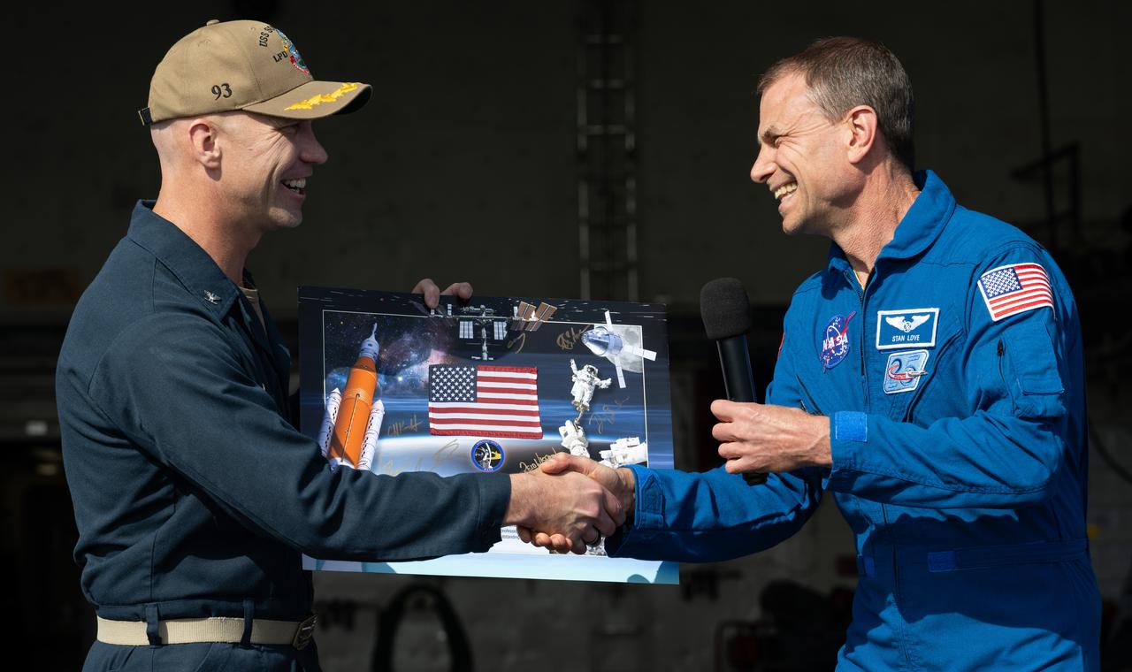 NASA astronaut Stan Love presents a montage to Capt. Andrew Koy, commanding officer of USS Somerset as NASA and Department of Defense teams participate in Underway Recovery Test-12 onboard USS Somerset off the coast of California, Saturday, March 29, 2025. During the test, NASA and Department of Defense teams are practicing to ensure recovery procedures are validated as NASA plans to send the Artemis II astronauts around the Moon and splashdown in the Pacific Ocean.  Photo Credit: (NASA/Joel Kowsky)