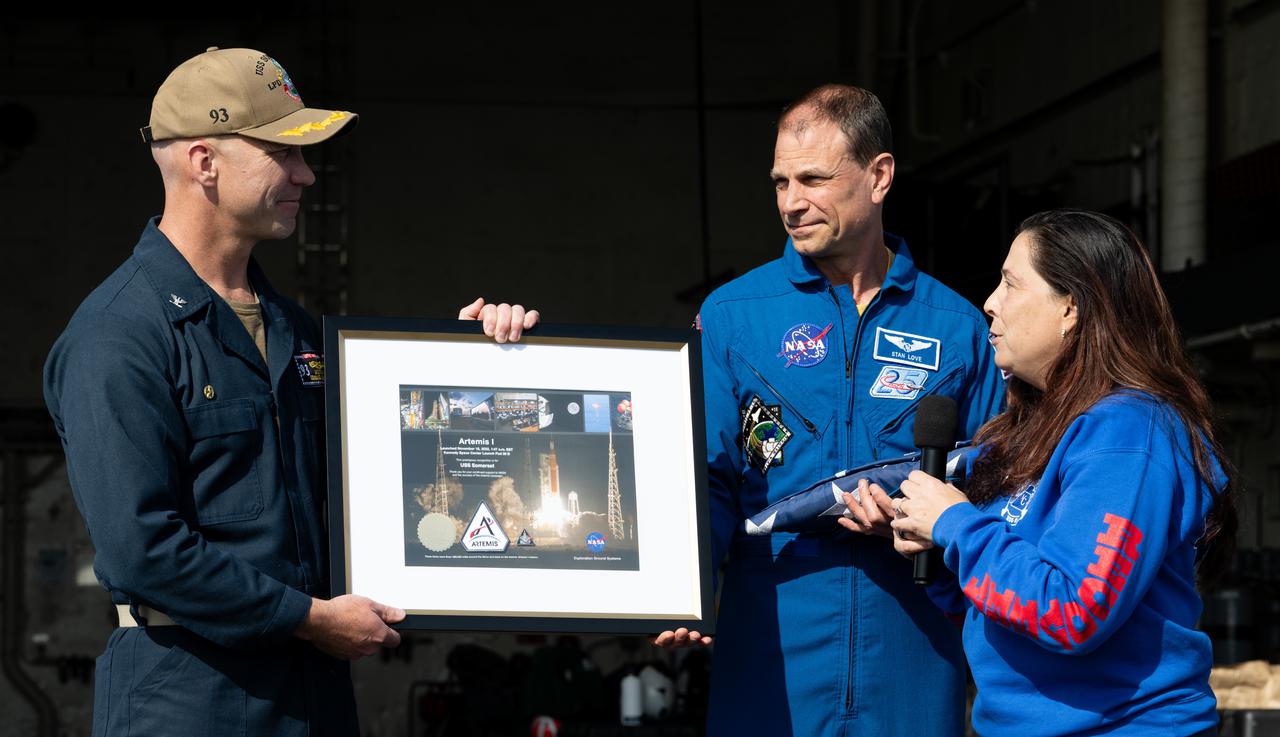 Lili Villarreal, Artemis landing and recovery director with Exploration Ground Systems, right, and NASA astronaut Stan Love present a montage to Capt. Andrew Koy, commanding officer of USS Somerset as NASA and Department of Defense teams participate in Underway Recovery Test-12 onboard USS Somerset off the coast of California, Saturday, March 29, 2025. During the test, NASA and Department of Defense teams are practicing to ensure recovery procedures are validated as NASA plans to send the Artemis II astronauts around the Moon and splashdown in the Pacific Ocean.  Photo Credit: (NASA/Joel Kowsky)