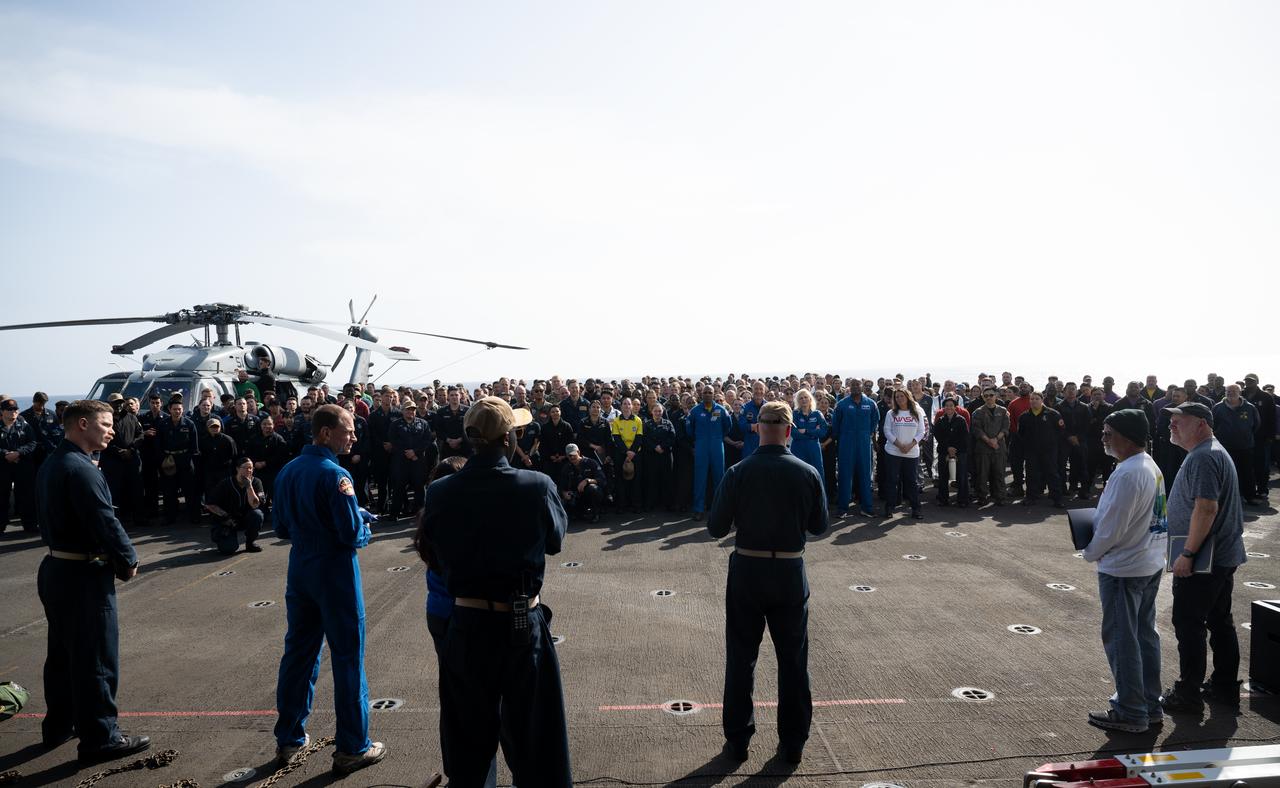 Capt. Andrew Koy, commanding officer of USS Somerset addresses NASA and Department of Defense recovery team members during Underway Recovery Test-12 onboard USS Somerset off the coast of California, Saturday, March 29, 2025. During the test, NASA and Department of Defense teams are practicing to ensure recovery procedures are validated as NASA plans to send the Artemis II astronauts around the Moon and splashdown in the Pacific Ocean. Photo Credit: (NASA/Joel Kowsky)