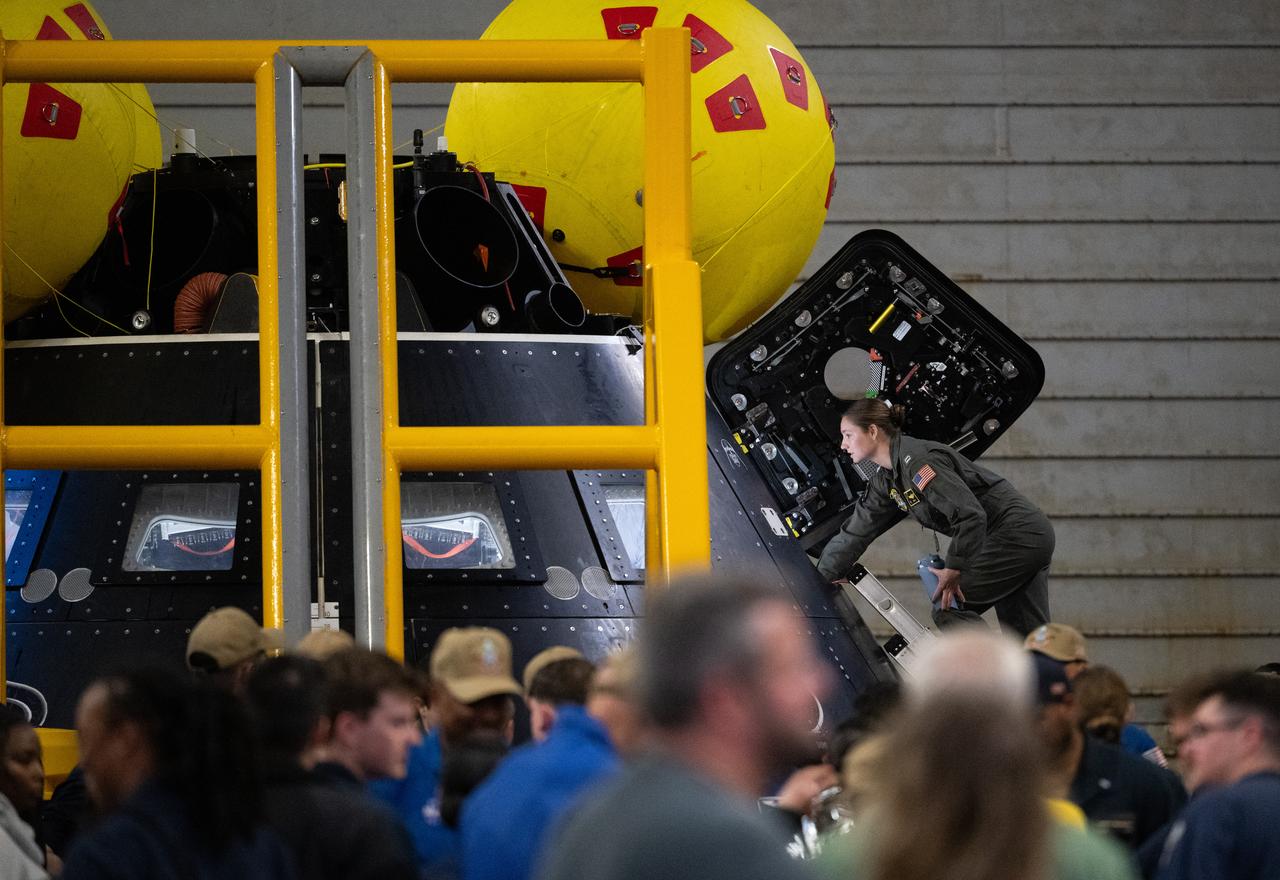 Members of Department of Defense recovery view the Crew Module Test Article (CMTA) during Underway Recovery Test-12 onboard USS Somerset off the coast of California, Saturday, March 29, 2025. During the test, NASA and Department of Defense teams are practicing to ensure recovery procedures are validated as NASA plans to send the Artemis II astronauts around the Moon and splashdown in the Pacific Ocean.  Photo Credit: (NASA/Joel Kowsky)