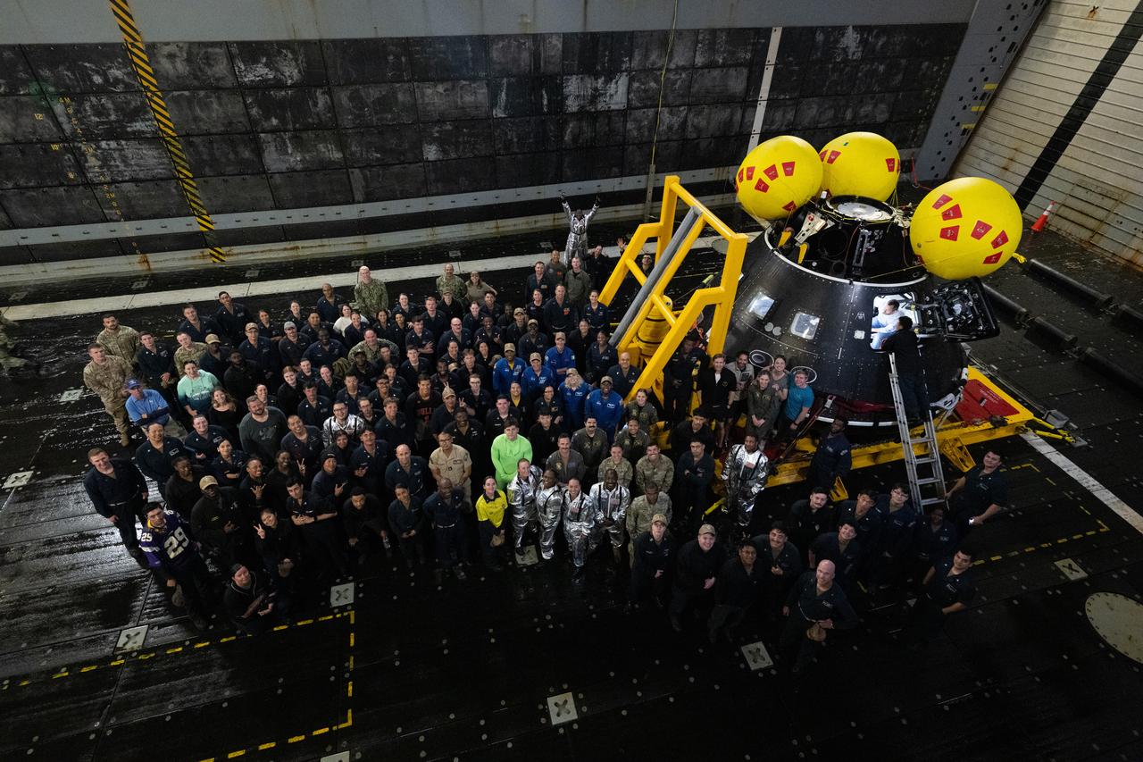 Members of NASA and Department of Defense Artemis recovery teams pose for a picture with NASA astronauts Victor Glover, Dinez Burnham, Andre Douglas, Stan Love, and ESA (European Space Agency) astronaut Luca Parmitano alongside the Crew Module Test Article (CMTA) during Underway Recovery Test-12 onboard USS Somerset off the coast of California, Saturday, March 29, 2025. During the test, NASA and Department of Defense teams are practicing to ensure recovery procedures are validated as NASA plans to send the Artemis II astronauts around the Moon and splashdown in the Pacific Ocean. Photo Credit: (NASA/Joel Kowsky)