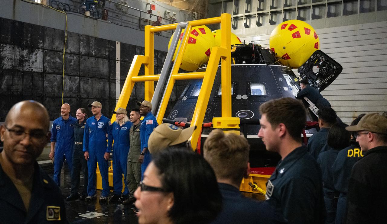 Members of Department of Defense Artemis recovery team view the Crew Module Test Article (CMTA) and have an opportunity to take pictures with ESA (European Space Agency) astronaut Luca Parmitano, and NASA astronauts Stan Love, Deniz Burnham, and Andre Douglas during Underway Recovery Test-12 onboard USS Somerset off the coast of California, Saturday, March 29, 2025. During the test, NASA and Department of Defense teams are practicing to ensure recovery procedures are validated as NASA plans to send the Artemis II astronauts around the Moon and splashdown in the Pacific Ocean.  Photo Credit: (NASA/Joel Kowsky)