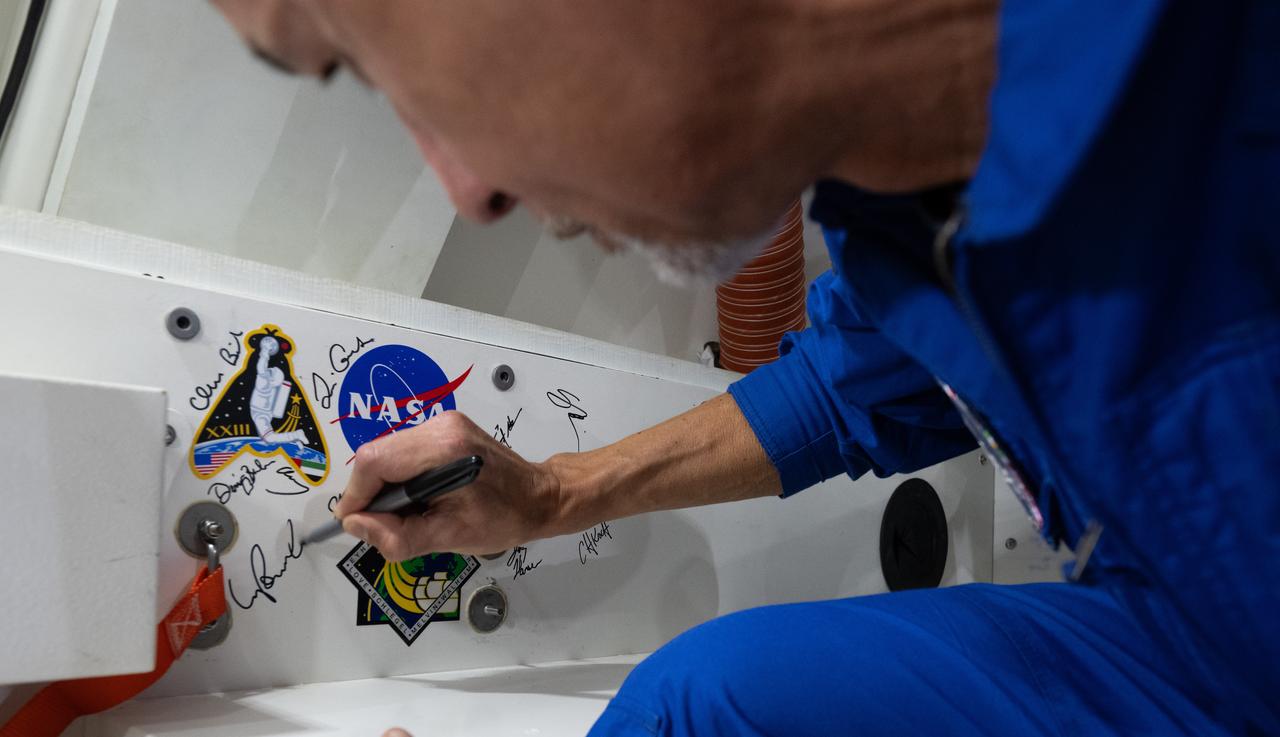 ESA (European Space Agency) astronaut Luca Parmitano signs an interior panel of the Crew Module Test Article (CMTA) during Underway Recovery Test-12 onboard USS Somerset off the coast of California, Saturday, March 29, 2025. During the test, NASA and Department of Defense teams are practicing to ensure recovery procedures are validated as NASA plans to send the Artemis II astronauts around the Moon and splashdown in the Pacific Ocean.  Photo Credit: (NASA/Joel Kowsky)