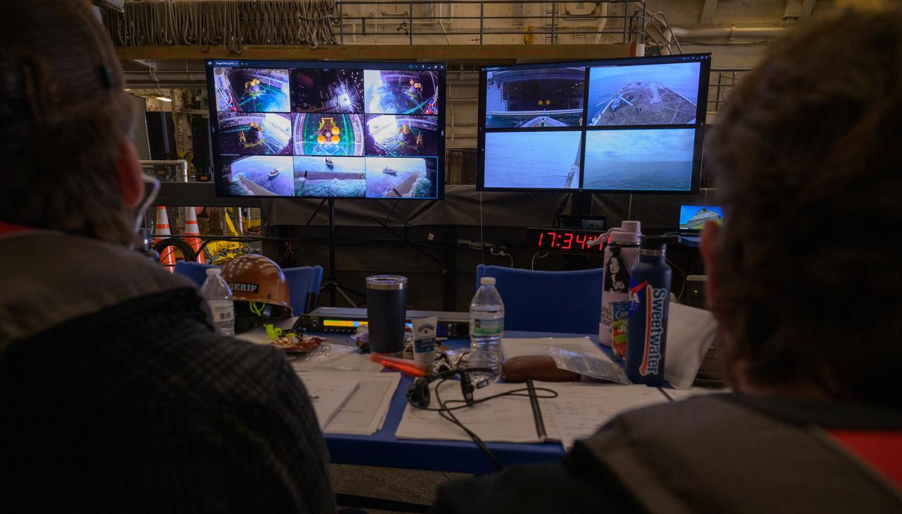 Monitors show various views of the well deck of USS Somerset as teams practice recovering the Crew Module Test Article (CMTA), a full scale mockup of the Orion spacecraft, during Underway Recovery Test-12 onboard USS Somerset off the coast of California, Saturday, March 29, 2025. During the test, NASA and Department of Defense teams are practicing to ensure recovery procedures are validated as NASA plans to send Artemis II around the Moon and splashdown in the Pacific Ocean. Photo Credit: (NASA/Bill Ingalls)