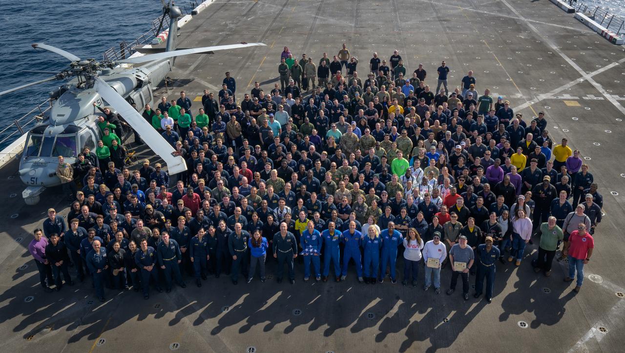 Members of NASA and Department of Defense recovery team pose for a group photograph on the flight deck of USS Somerset after practicing Artemis recovery operations during Underway Recovery Test-12 off the coast of California, Saturday, March 29, 2025. During the test, NASA and Department of Defense teams are practicing to ensure recovery procedures are validated as NASA plans to send Artemis II around the Moon and splashdown in the Pacific Ocean.  Photo Credit: (NASA/Bill Ingalls)