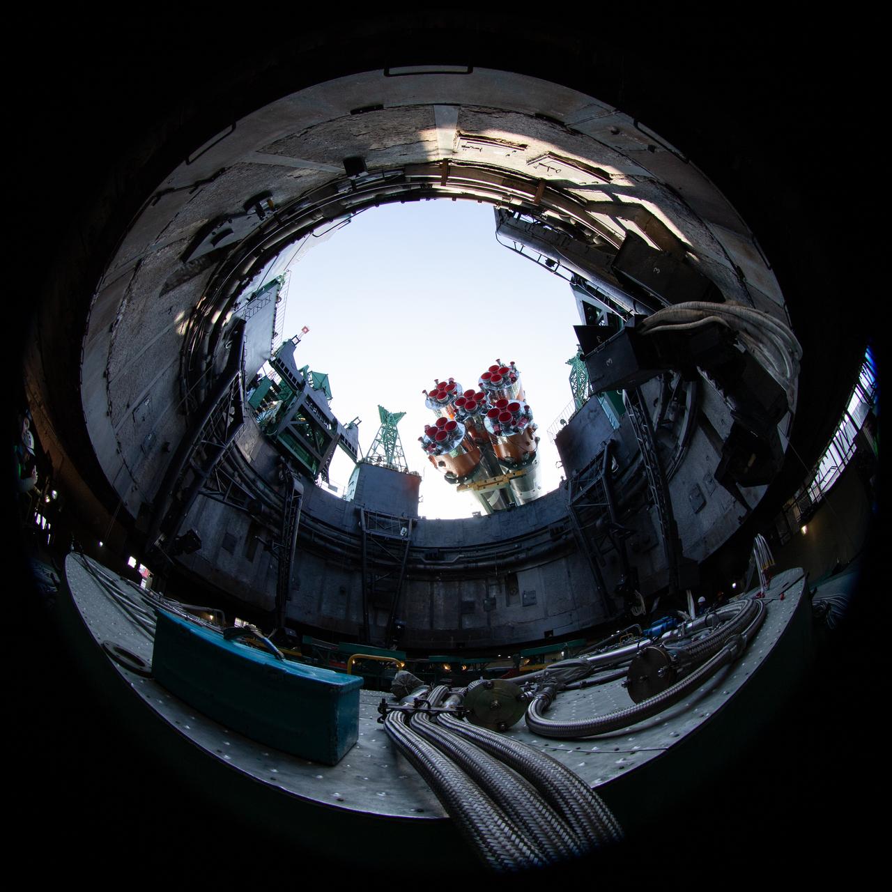 In this image taken with a circular fisheye lens, the Soyuz rocket is seen as it is raised into a vertical position after being rolled out by train to the launch pad at Site 31, Saturday, April 5, 2025, at the Baikonur Cosmodrome in Kazakhstan. Expedition 73 crewmembers: NASA astronaut Jonny Kim, and Roscosmos cosmonauts Sergey Ryzhikov and Alexey Zubritskiy, are scheduled to launch aboard their Soyuz MS-27 spacecraft on April 8. Photo Credit: (NASA/Joel Kowsky)