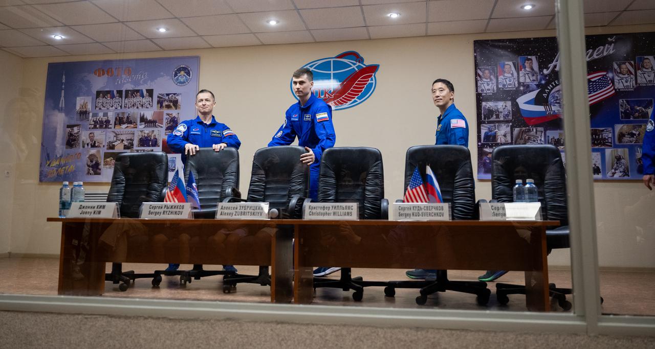 Roscosmos cosmonauts Sergey Ryzhikov, left, Alexey Zubritskiy, and NASA astronaut Jonny Kim are seen in quarantine, behind glass, before the start of a press conference, Monday, April 7, 2025 a the Cosmonaut Hotel in Baikonur, Kazakhstan. Kim, Ryzhikov, Zubritskiy are scheduled to launch aboard their Soyuz MS-27 spacecraft on April 8. Photo Credit: (NASA/Joel Kowsky)