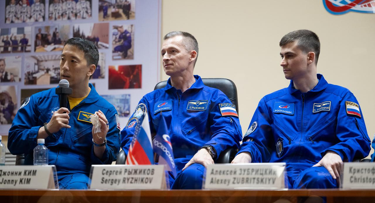 NASA astronaut Jonny Kim, left, and Roscosmos cosmonauts Sergey Ryzhikov and Alexey Zubritskiy seen in quarantine, behind glass, during a press conference, Monday, April 7, 2025 a the Cosmonaut Hotel in Baikonur, Kazakhstan. Kim, Ryzhikov, Zubritskiy are scheduled to launch aboard their Soyuz MS-27 spacecraft on April 8. Photo Credit: (NASA/Joel Kowsky)
