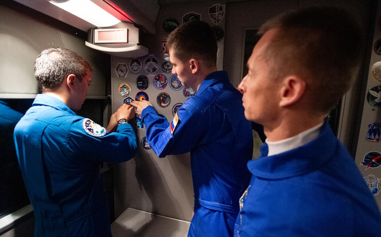 NASA astronaut Jonny Kim, left, and Roscosmos cosmonaut \Alexey Zubritskiy, center, place an Expedition 73 sticker on the wall of the bus taking them to suit-up for their Soyuz launch to the International Space Station along with Roscosmos cosmonaut Sergey Ryzhikov, Tuesday, April 8, 2025 (April 7 Eastern Time), in Baikonur, Kazakhstan. The launch will send Kim, Ryzhikov, Zubritskiy on a mission to the International Space Station. Photo Credit: (NASA/GCTC/Pavel Shvets)