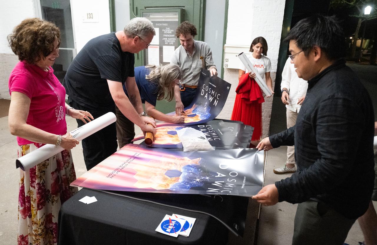 Attendees pick up movie posters for the new NASA+ documentary “Cosmic Dawn: The Untold Story of the James Webb Space Telescope” following a screening at at the Greenbelt Cinema, Wednesday, June 11, 2025, in Greenbelt, Maryland. Featuring never-before-seen footage, Cosmic Dawn offers an unprecedented glimpse into the assembly, testing, and launch of NASA’s James Webb Space Telescope.   Photo Credit: (NASA/Joel Kowsky)