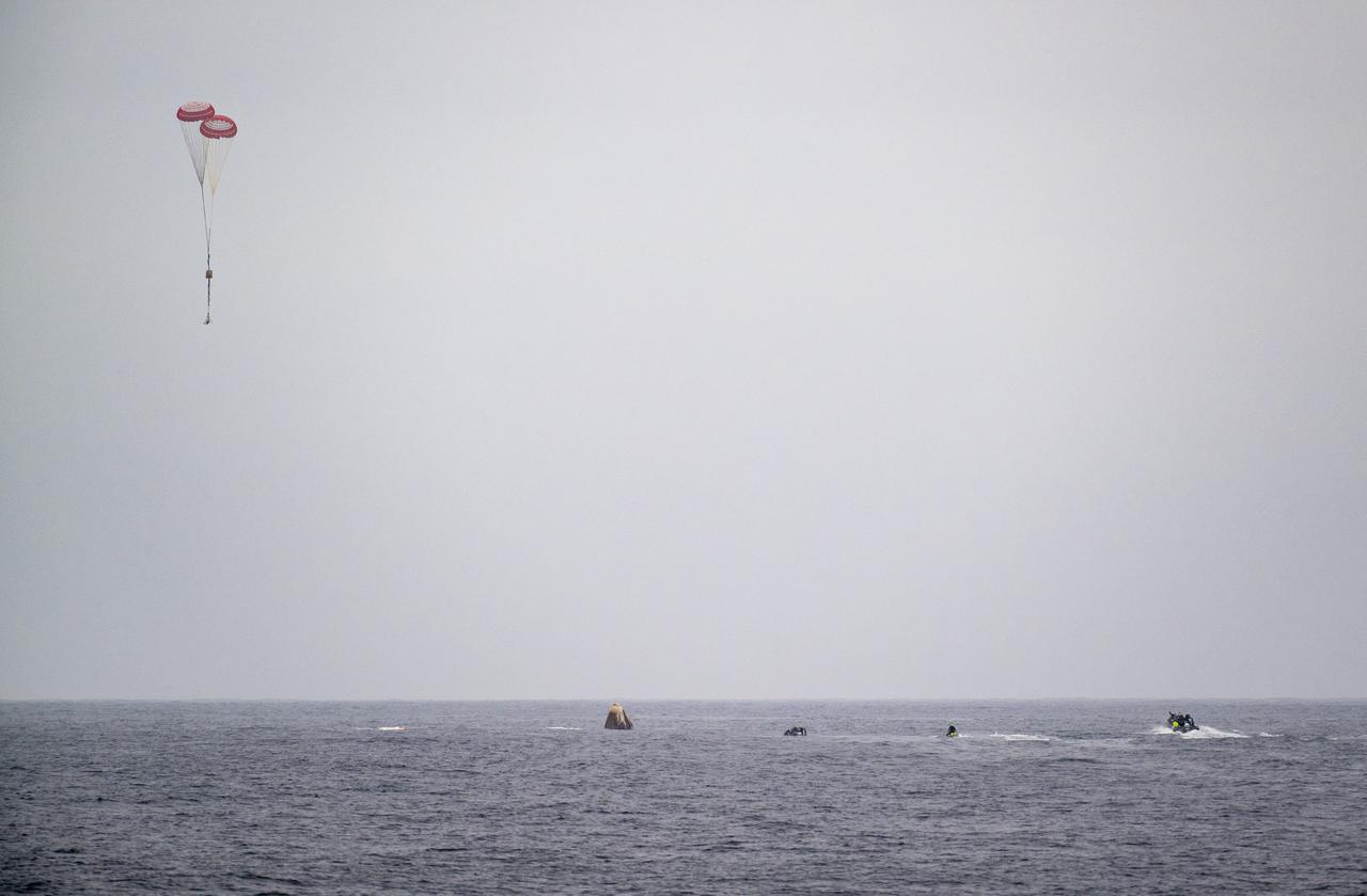 Support teams work around the SpaceX Dragon Endurance spacecraft shortly after it landed with NASA astronauts Anne McClain and Nichole Ayers, JAXA (Japan Aerospace Exploration Agency) astronaut Takuya Onishi, and Roscosmos cosmonaut Kirill Peskov aboard in the Pacific Ocean off the coast of San Diego, Calif., Saturday, Aug. 9,2025. McClain, Ayers, Onishi, and Peskov are returning after 147 days in space as part of Expedition 73 aboard the International Space Station. The drogue parachutes can also be seen in the sky behind the SpaceX Dragon Endurance spacecraft as they land in the Pacific Ocean. Photo Credit: (NASA/Keegan Barber)