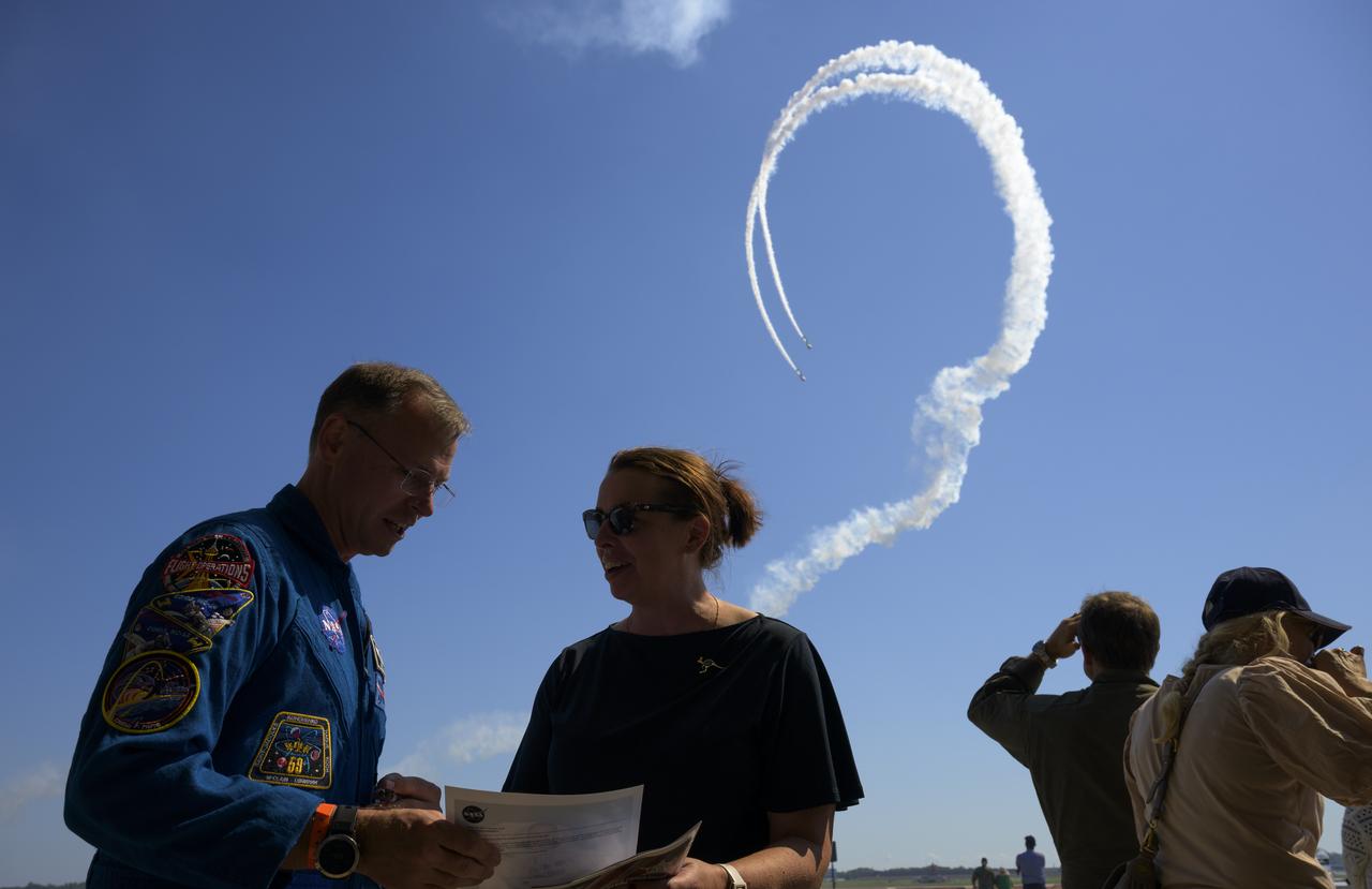 Warbird Thunder SNJ planes perform in the background as NASA astronaut Nick Hague meets with attendees, Friday, Sept. 12, 2025, during the Joint Base Andrews Air Show at Joint Base Andrews in Prince George's County, Maryland. Hague spent 171 days onboard the International Space Station as part of Expedition 72. Photo Credit: (NASA/Bill Ingalls)