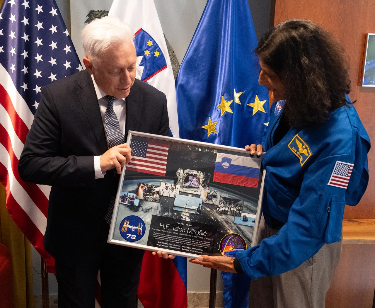On behalf of the Expedition 72 crew NASA astronaut Suni Williams presents Iztok Mirošič, Ambassador of the Republic of Slovenia to the United States to the United States, with a montage including flags of the United States and Slovenia that have been flown in space before participating in a panel discussion at the Embassy of Slovenia,  Wednesday, Sept. 17, 2025, in Washington. Williams, Don Pettit, Nick Hague, and Butch Wilmore served as part of Expedition 72 onboard the International Space Station.  Photo Credit: (NASA/Joel Kowsky)