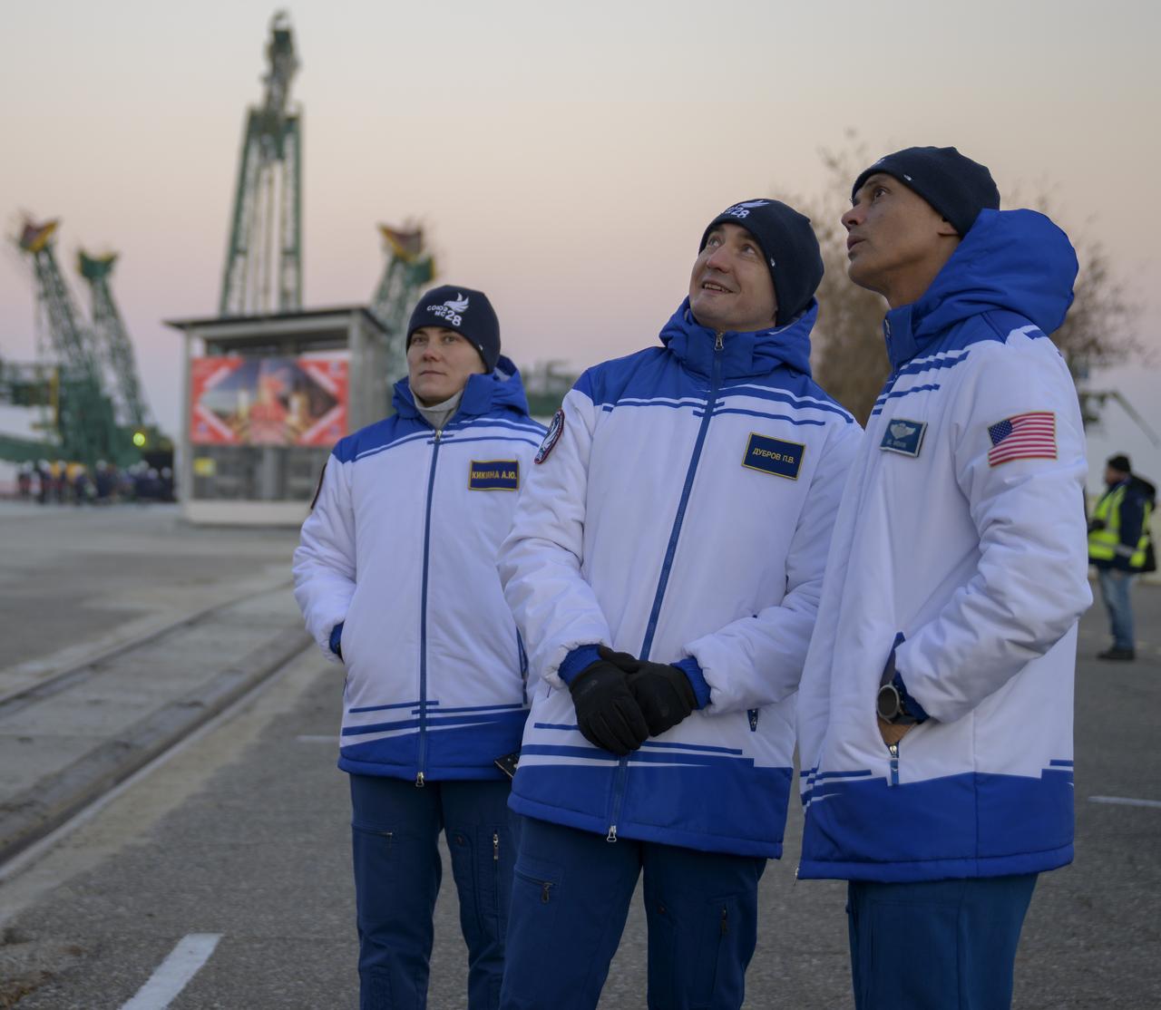 Expedition 74 backup crew members: Anna Kikina of Roscosmos, left, Petr Dubrov of Roscosmos, and Anil Menon of NASA, right, watch as the Soyuz rocket is rolled out by train to the launch pad, Monday, Nov. 24, 2025, at Site 31 of the Baikonur Cosmodrome in Kazakhstan. Expedition 74 crewmembers: NASA astronaut Chris Williams, Roscosmos cosmonauts Sergey Kud-Sverchkov and Sergey Mikaev are scheduled to launch aboard their Soyuz MS-28 spacecraft on November 27. Photo Credit: (NASA/Bill Ingalls)