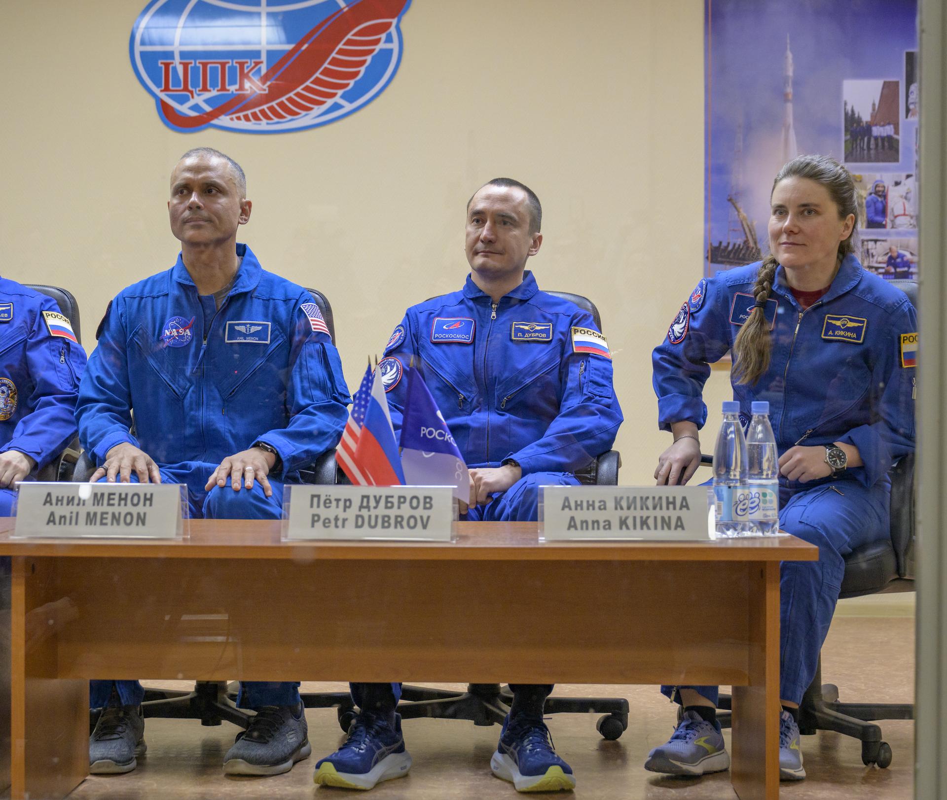 Expedition 74 backup crew members Anil Menon of NASA, left, and Roscosmos cosmonauts Petr Dubrov, and Anna Kikina, right, are seen in quarantine, behind glass, during a press conference, Wednesday, Nov. 26, 2025 at the Cosmonaut Hotel in Baikonur, Kazakhstan. Expedition 74 crewmembers: NASA astronaut Chris Williams, Roscosmos cosmonauts Sergey Kud-Sverchkov and Sergei Mikaev, are scheduled to launch aboard their Soyuz MS-28 spacecraft on November 27. Photo Credit: (NASA/Bill Ingalls)