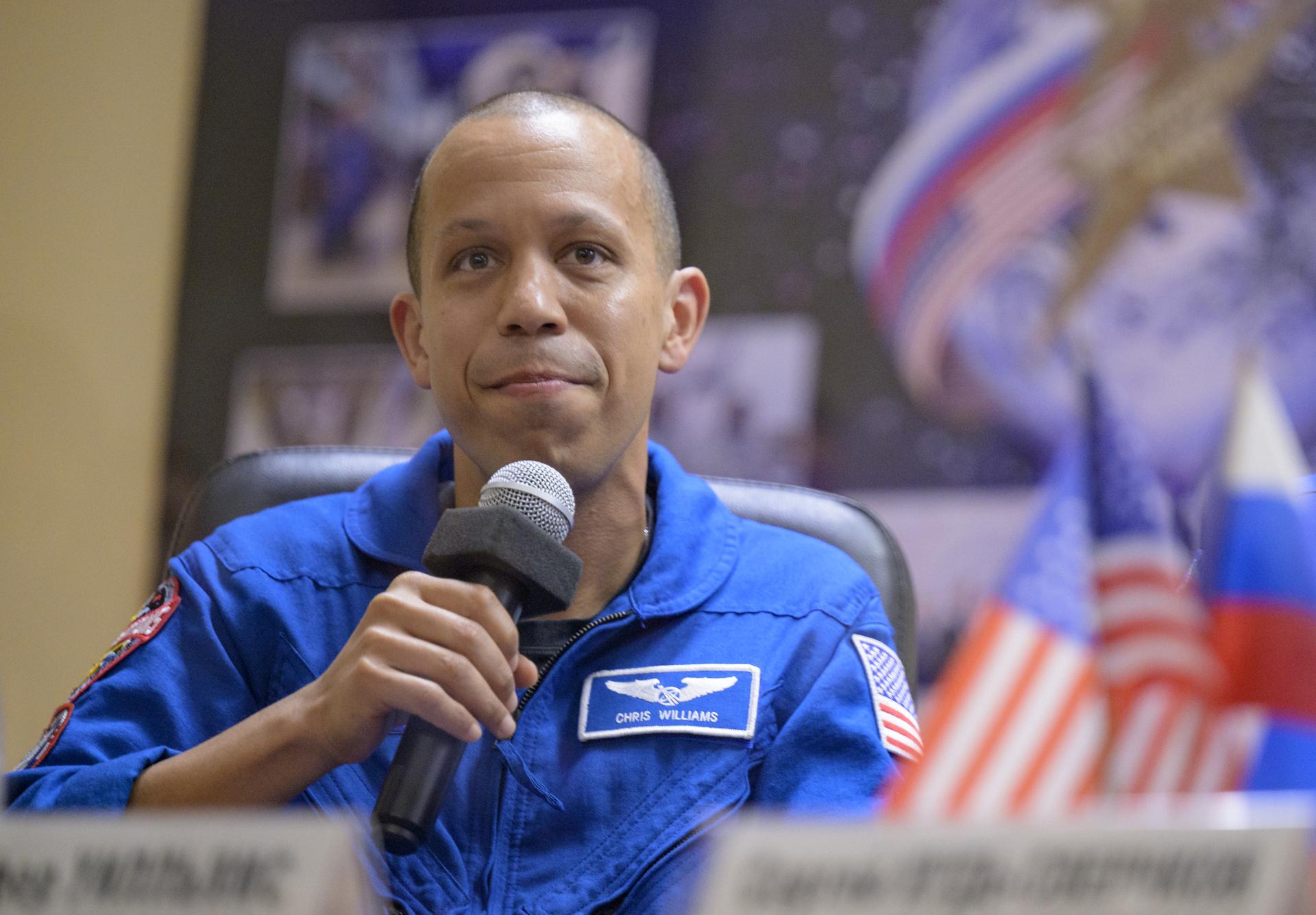 NASA astronaut Chris Williams is seen in quarantine, behind glass, during a press conference, Wednesday, Nov. 26, 2025 at the Cosmonaut Hotel in Baikonur, Kazakhstan. Expedition 74 crewmembers: NASA astronaut Chris Williams, Roscosmos cosmonauts Sergey Kud-Sverchkov and Sergei Mikaev, are scheduled to launch aboard their Soyuz MS-28 spacecraft on November 27. Photo Credit: (NASA/Bill Ingalls)