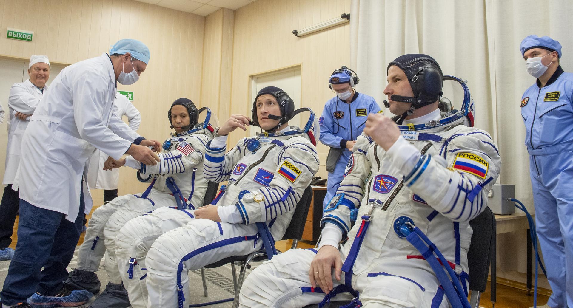 NASA astronaut Chris Williams, left, Roscosmos cosmonauts Sergey Kud-Sverchkov, and Sergei Mikaev, right, are helped into their Russian Sokol suits as they prepare for their Soyuz launch to the International Space Station Thursday, Nov. 27, 2025 in Baikonur, Kazakhstan. Photo Credit: (NASA/GCTC/Pavel Shvets)