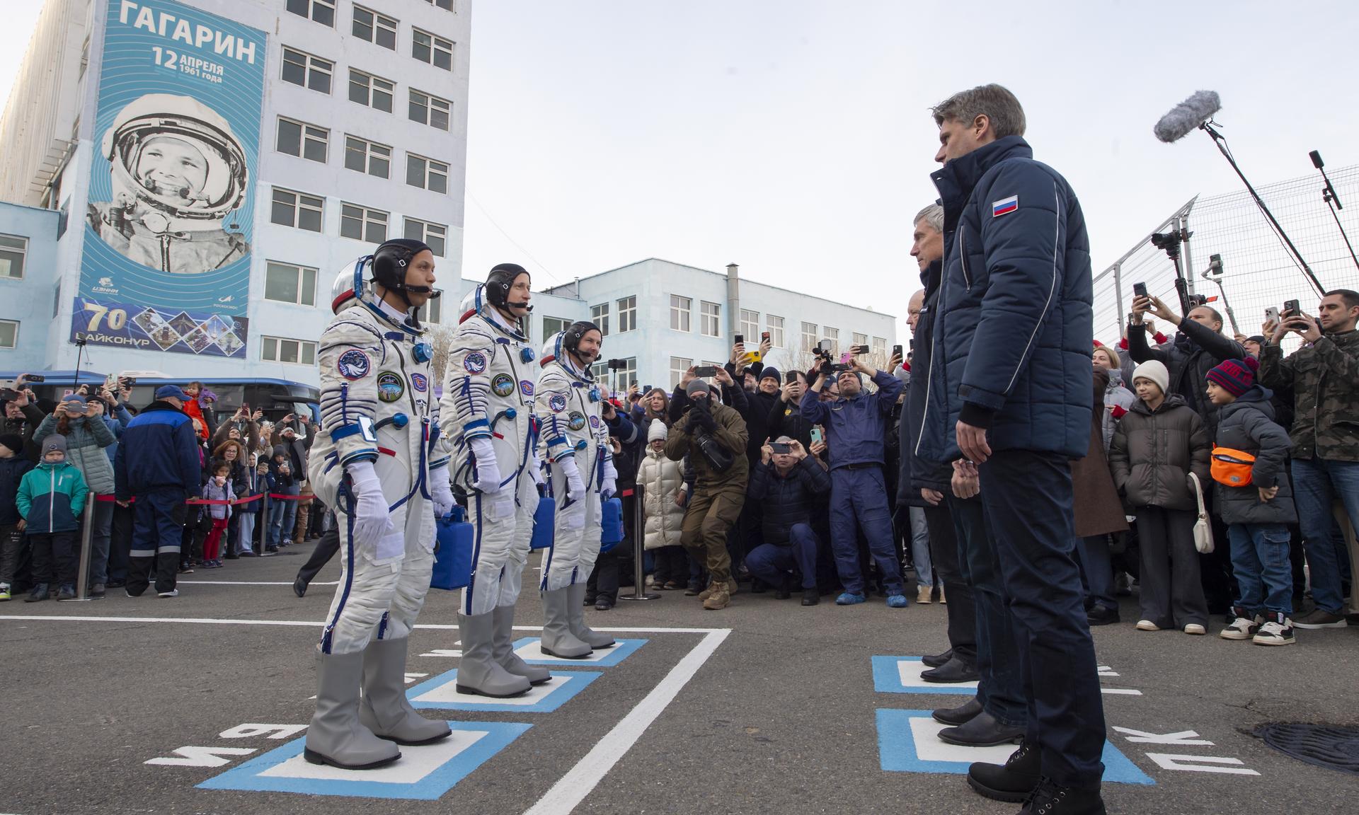 NASA astronaut Chris Williams, left, and Roscosmos cosmonauts Sergey Kud-Sverchkov, and Sergei Mikaev, right, receive approval to proceed to the launch pad by Roscosmos management ahead of their Soyuz launch to the International Space Station Thursday, Nov. 27, 2025 outside building 254, of the Baikonur Cosmodrome, Kazakhstan. Photo Credit: (NASA/GCTC/Pavel Shvets)