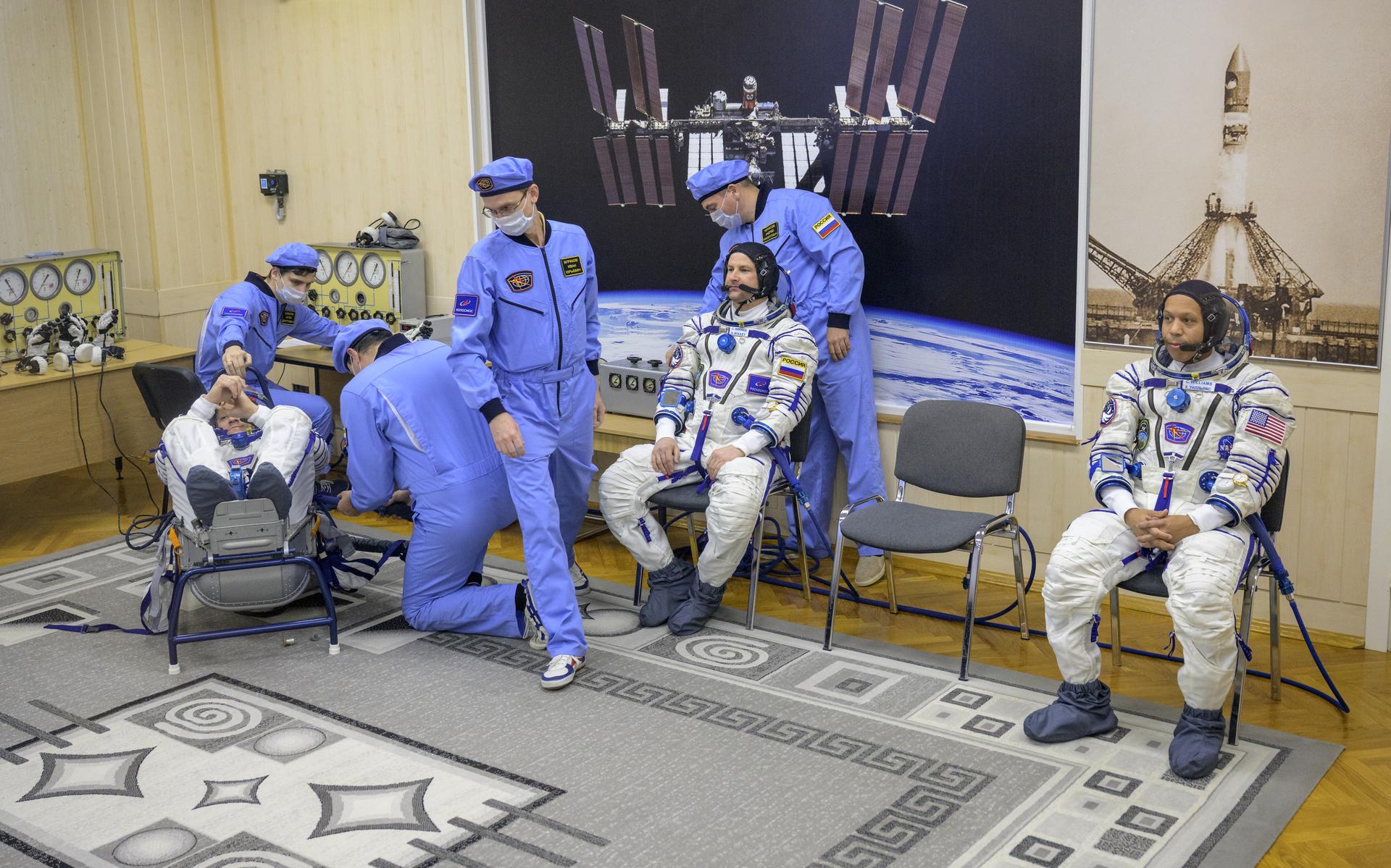 Roscosmos cosmonaut Sergey Kud-Sverchkov starts to have his Russian Sokol suit pressure checked as Roscosmos cosmonaut Sergei Mikaev, center, and NASA astronaut Chris Williams, right, wait, ahead of their Soyuz launch to the International Space Station Thursday, Nov. 27, 2025 in Baikonur, Kazakhstan. Photo Credit: (NASA/Bill Ingalls)