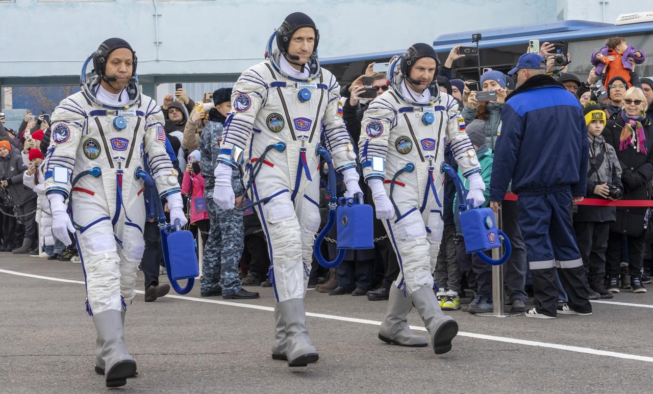 NASA astronaut Chris Williams, left, and Roscosmos cosmonauts Sergey Kud-Sverchkov, and Sergei Mikaev, right, depart building 254 of the Baikonur Cosmodrome, Kazakhstan ahead of their Soyuz launch to the International Space Station Thursday, Nov. 27, 2025. Photo Credit: (NASA/Victor Zelentsov)