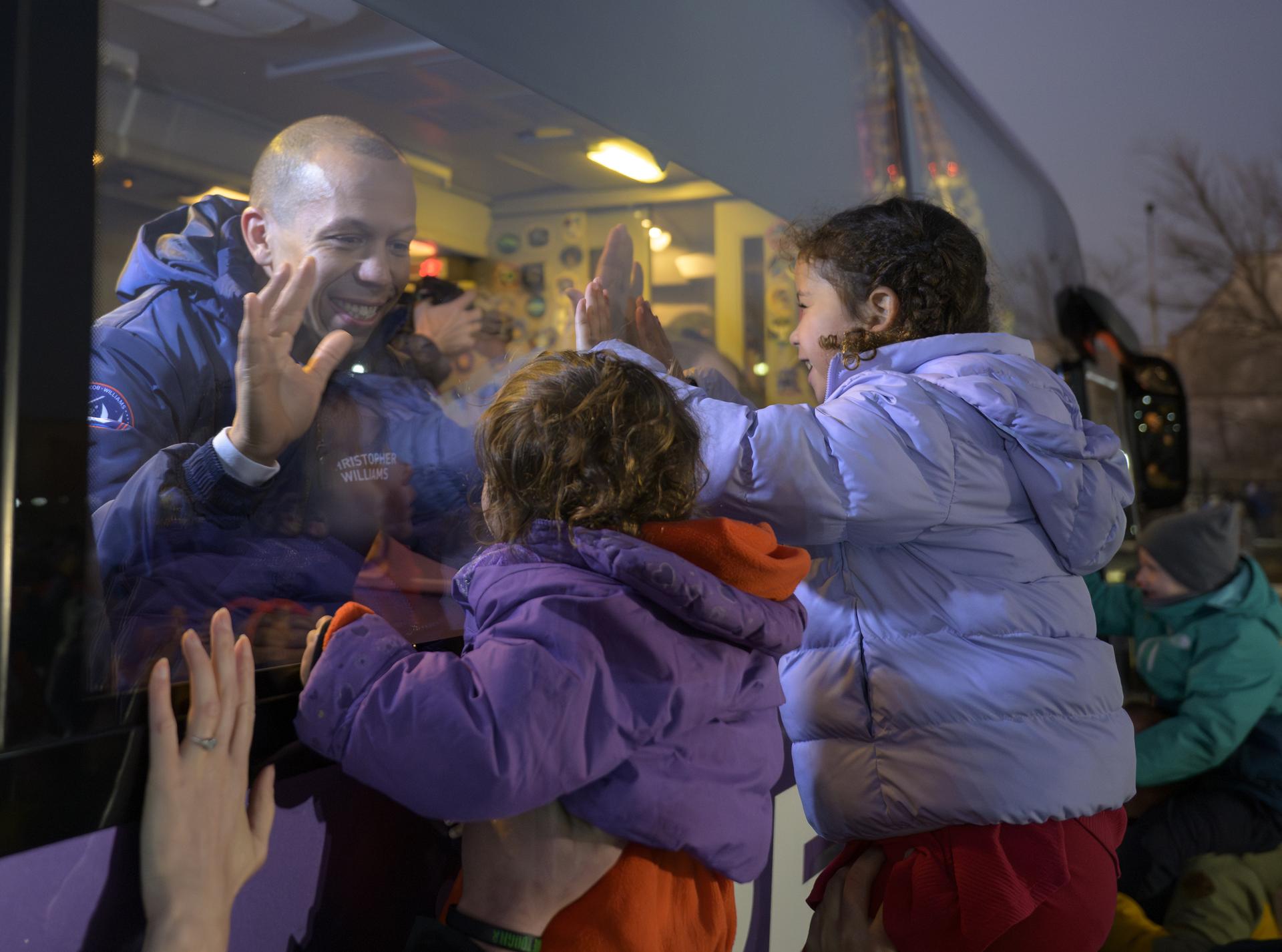 NASA astronaut Chris Williams puts his hands to the glass of the bus with his children, as he and fellow crewmembers, Roscosmos cosmonauts Sergey Kud-Sverchkov, and Sergei Mikaev, depart the Cosmonaut Hotel to suit-up for their Soyuz launch, Thursday, Nov. 27, 2025, in Baikonur, Kazakhstan. The launch will send Williams, Kud-Sverchkov and Mikaev, on a mission to the International Space Station. Photo Credit: (NASA/Bill Ingalls)