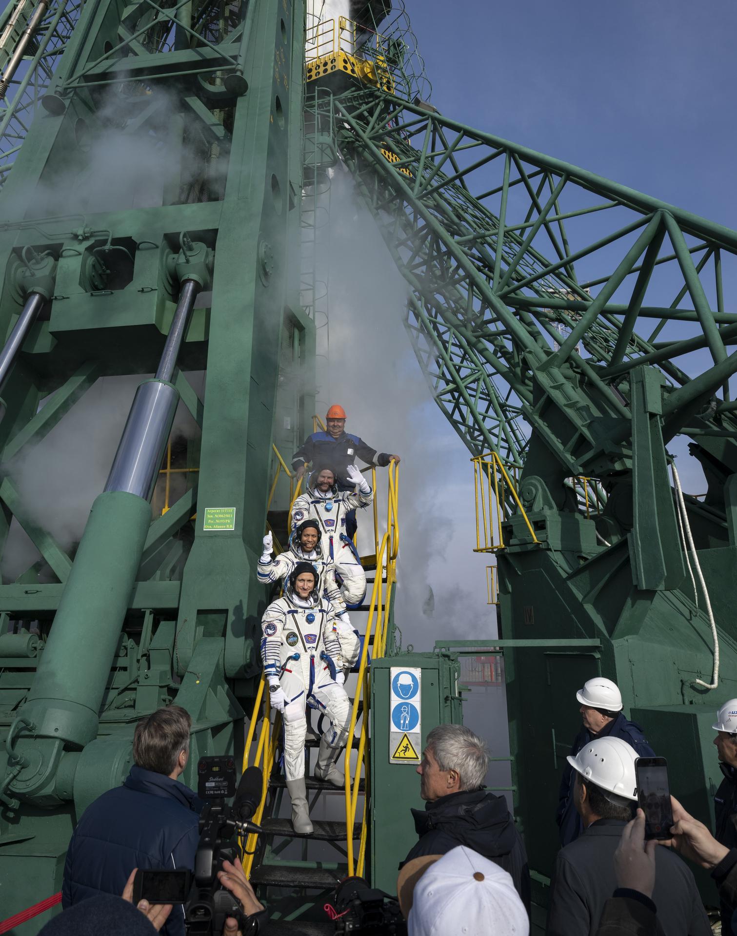 Roscosmos cosmonaut Sergei Mikaev, top,  NASA astronaut Chris Williams, middle, and  Roscosmos cosmonaut Sergey Kud-Sverchkov, wave farewell prior to boarding the Soyuz MS-28 spacecraft for launch, Thursday, Nov. 27, 2025 at the Baikonur Cosmodrome in Kazakhstan. Launch of the Soyuz rocket will send the trio on a mission to the International Space Station. Photo Credit: (NASA/Bill Ingalls)
