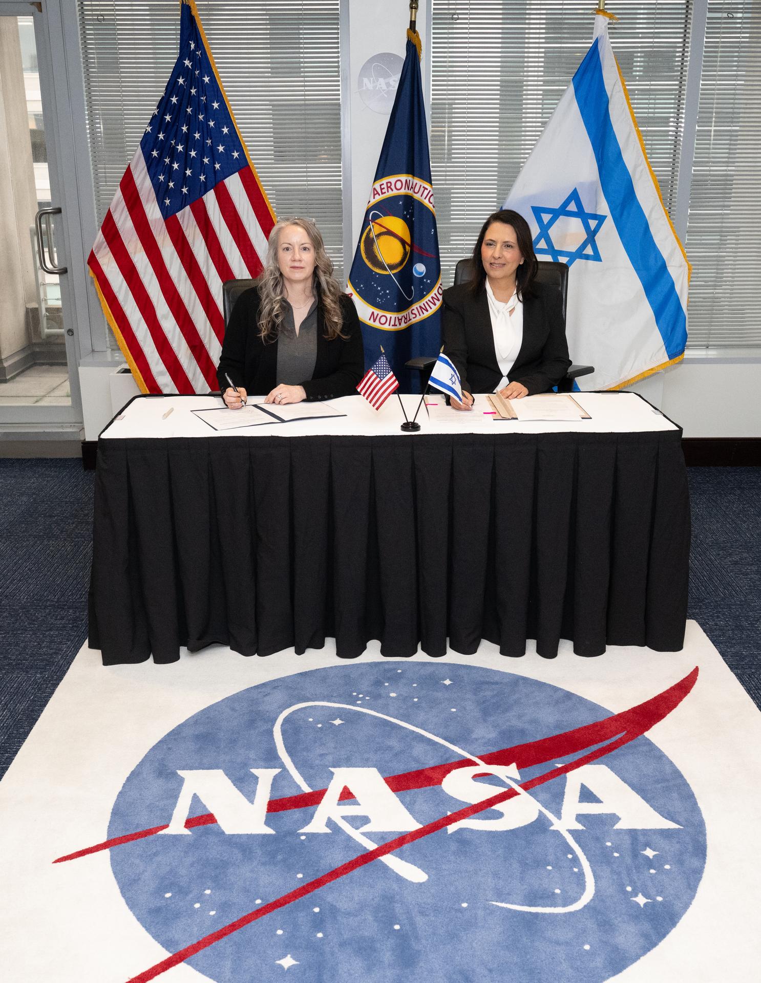 Meredith McKay, acting associate administrator for NASA’s Office of International and Interagency Relations, left, and Israel’s Minister for Innovation, Science, and Technology Gila Gamliel sign the US-Israel Space Cooperation Framework Agreement Extension, Wednesday, Dec. 10, 2025, at the Mary W. Jackson NASA Headquarters building in Washington. Photo Credit: (NASA/Joel Kowsky)